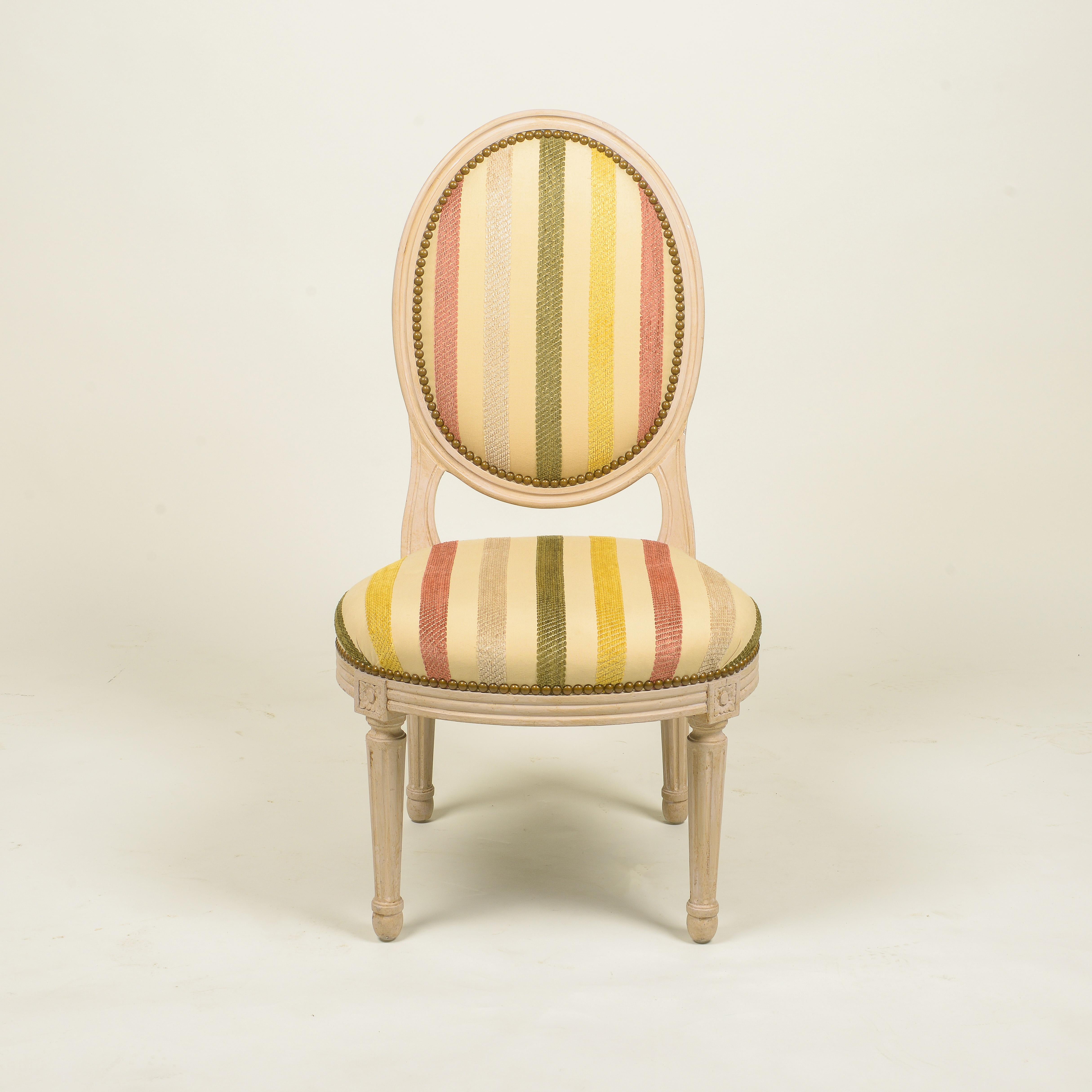 The padded oval back and seat within a fluted frame; raised on stop-fluted tapering legs headed by flowerheads; upholstered in a tapestry polychrome stripe with nailheads.