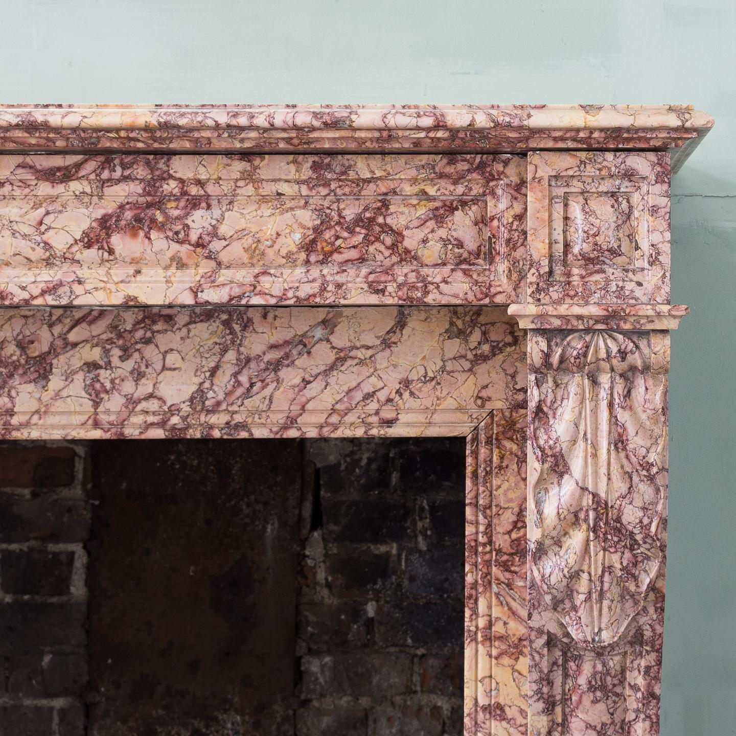 A 19th century French Louis XVI style pink brocatello fireplace, with deep molded rectangular shelf above paneled frieze and end blocks, on volute jambs.

Dimensions: 101cm (39¾