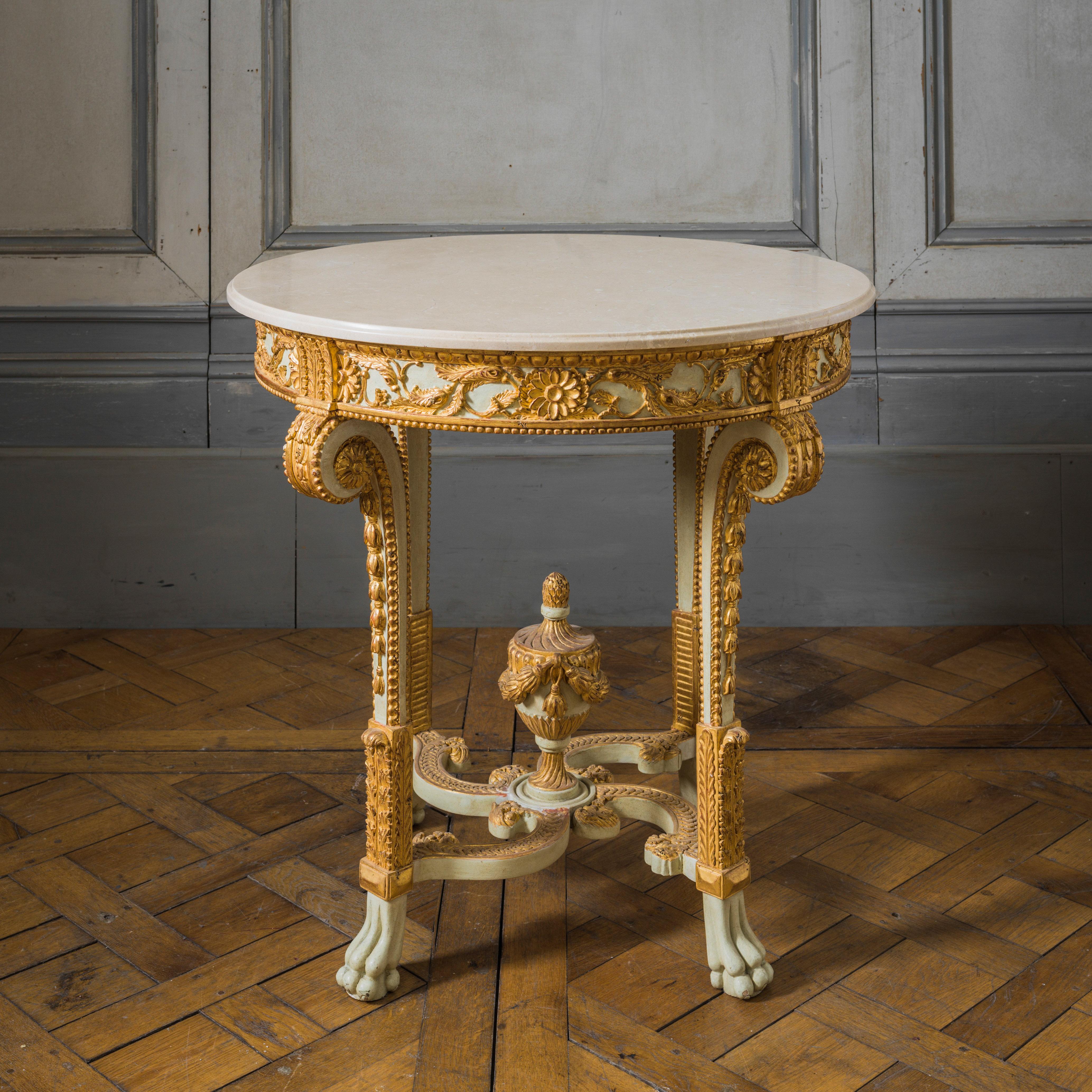 Louis XVI style round console table. Hand-carved by master craftsmen and hand finished in an aged polychrome gilded and ecru/white patina made using traditional methods and materials. 
Crema Marfill 20mm honed, sealed and Waxed marble top with a