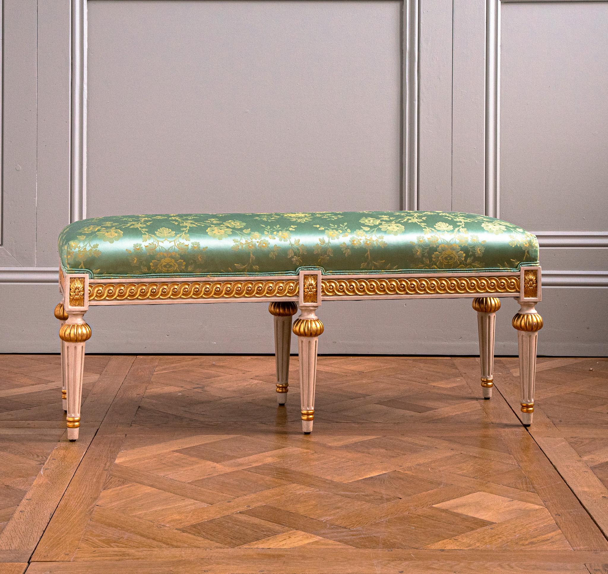 Banco de madera dorada policromada de estilo Luis XVI, pintado en un blanco antiguo con reflejos dorados y tapizado con una tela de Tassinari y Chatel.
