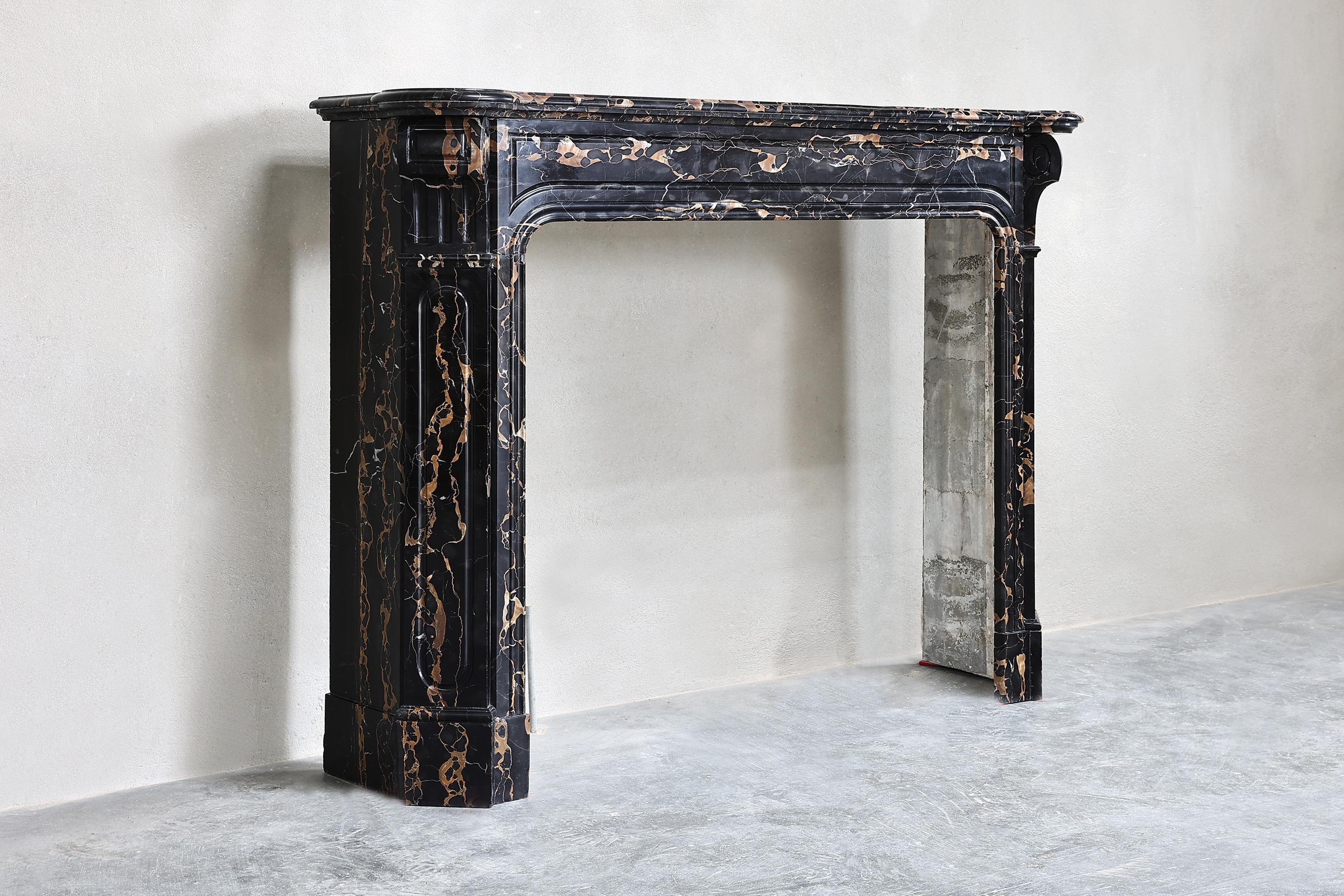 Beautiful antique fireplace of Portoro marble from Italy. This type of marble is dark brown in color with brown/gold veins, a very warm color scheme! The fireplace is sleek and chic in design and has graceful legs. That makes the fireplace a special