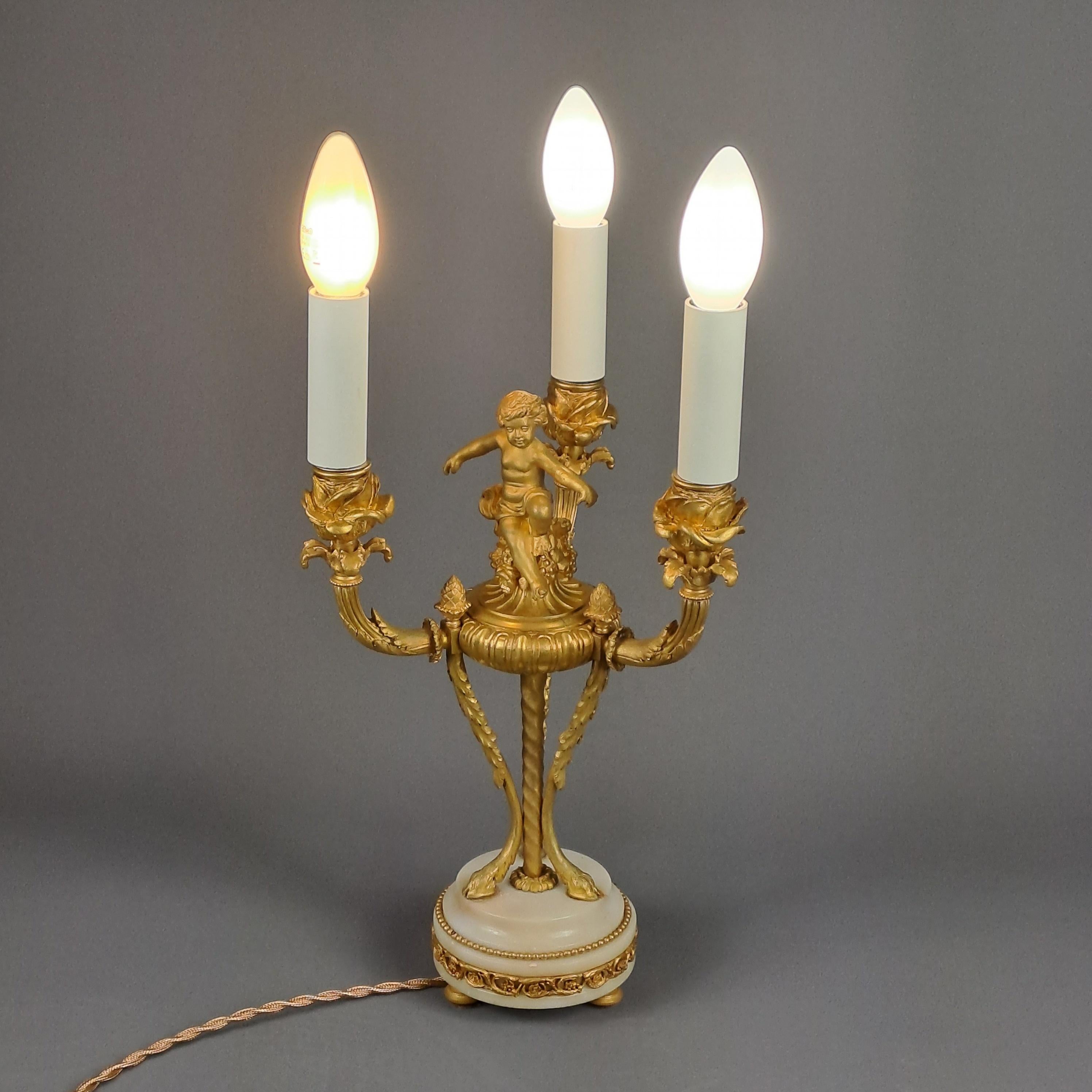 Candlestick with three Louis XVI Style sconces in gilded bronze and white marble base.

Mounted as a desk or mantel lamp, it has a very beautiful finely chiseled decoration with in particular a putto in the center balanced on a floral and vegetal