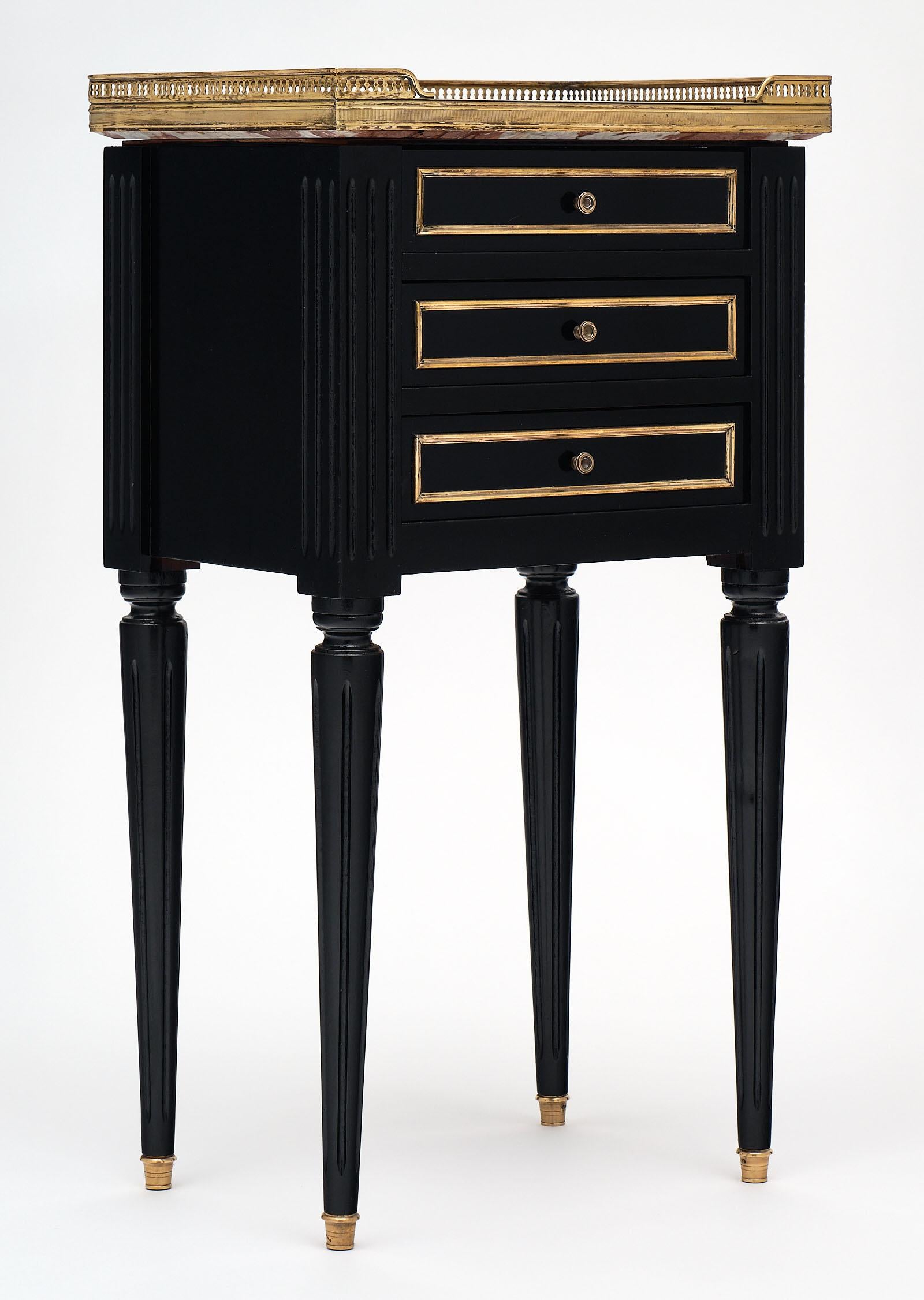 This French antique Louis XVI style side table boasts a unique red marble “rouge royal” top with striking white veining. Original brass gallery and trim on all three dovetailed drawers. This piece has been ebonized and finished with a French polish