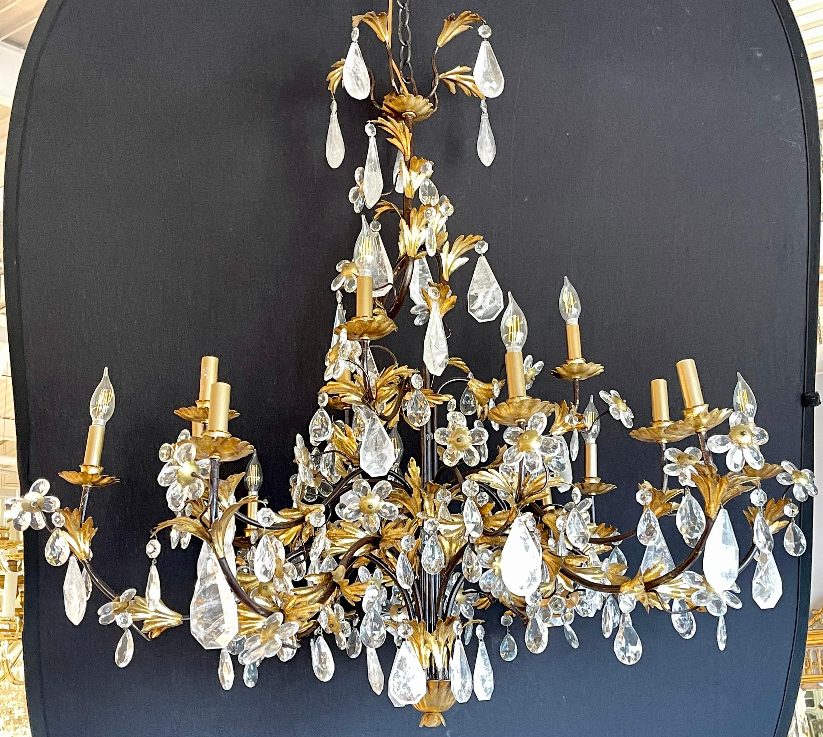A Hollywood Regency or Louis XVI Style chandelier having many large and impressive rock crystals prisms hanging from an ebony and gilt metal frame of floral, swag and large crystal roses. This finely craft stunning chandelier is not served well by