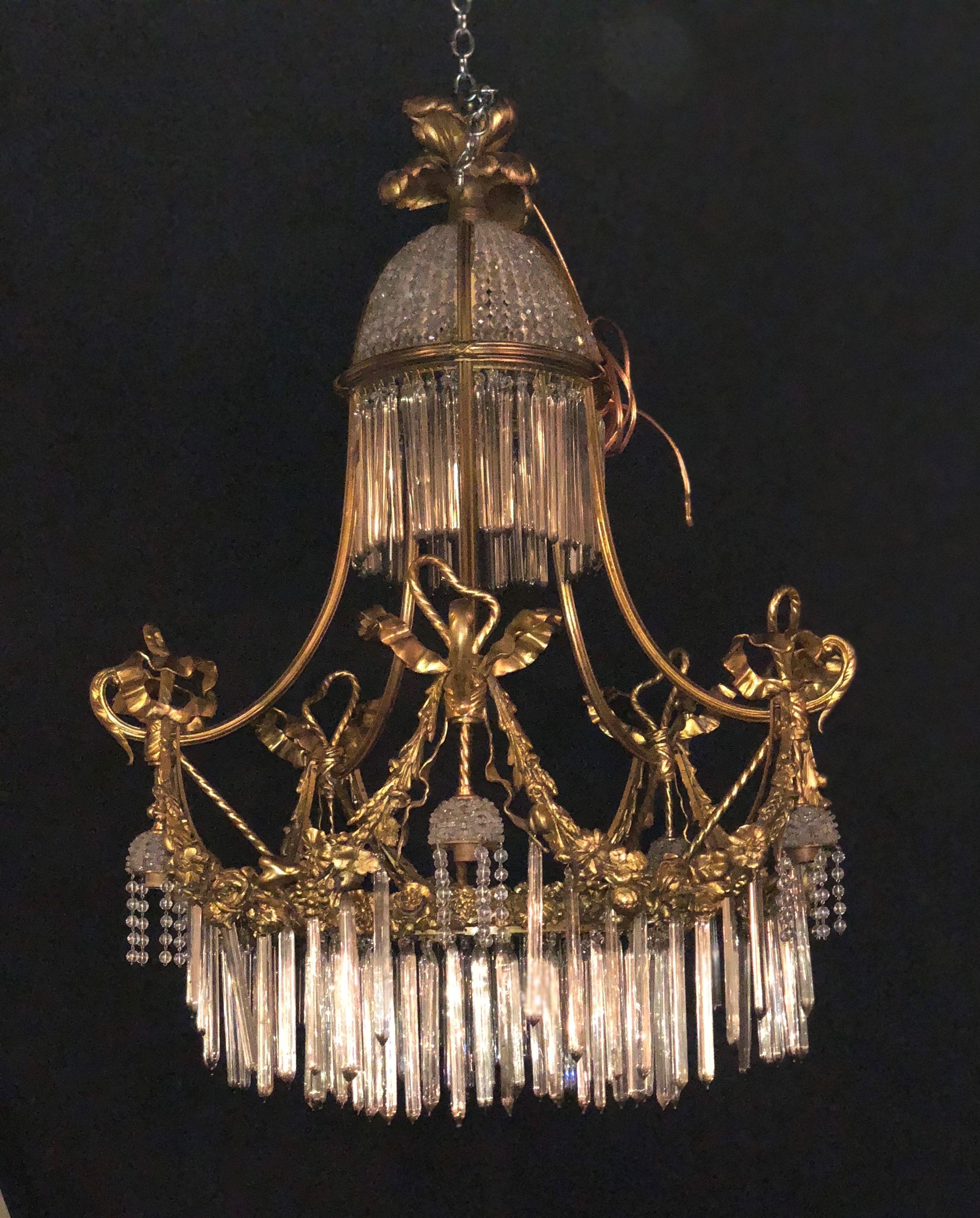 A Louis XVI style doré bronze and crystal balloon form chandelier. The finely chased bronze ribbon and bow finial above a balloon form of crystal and gilt bronze make this sleek and stylish chandelier a must have. Six outer lights and four