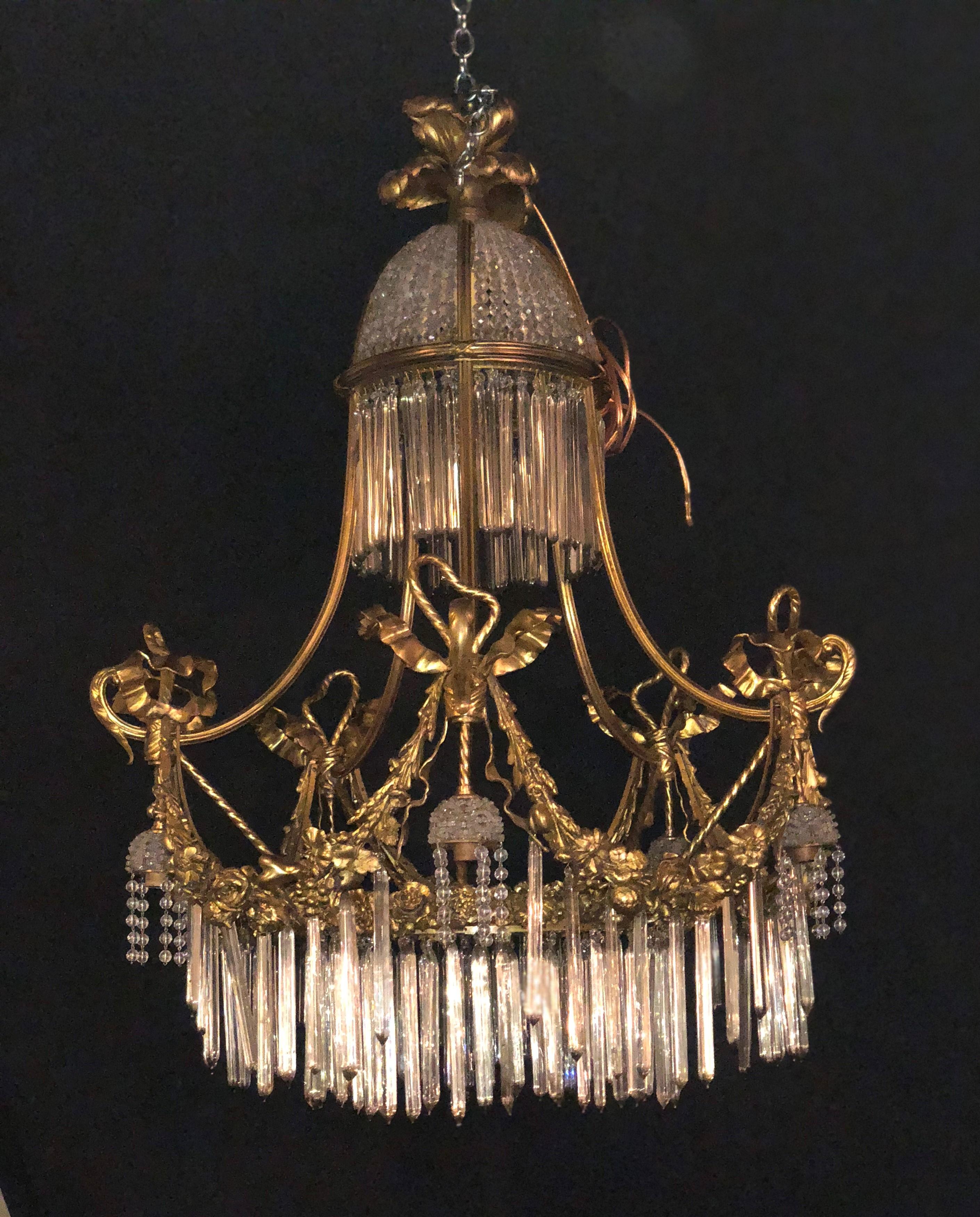 A Louis XVI style doré bronze and crystal balloon form chandelier. The finely chased bronze ribbon and bow finial above a balloon form of crystal and gilt bronze make this sleek and stylish chandelier a must have. Six outer lights and four inside.