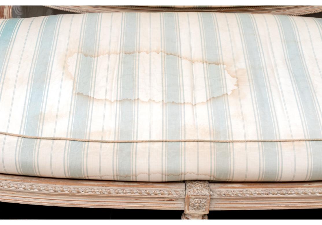 A Louis XVI style settee with a heavily carved frame featuring the armrests of the sofa are prominently carved in the form of ram's heads in the neoclassical style. The sofa with a central carved oval frame surmounted with a pair of carved birds