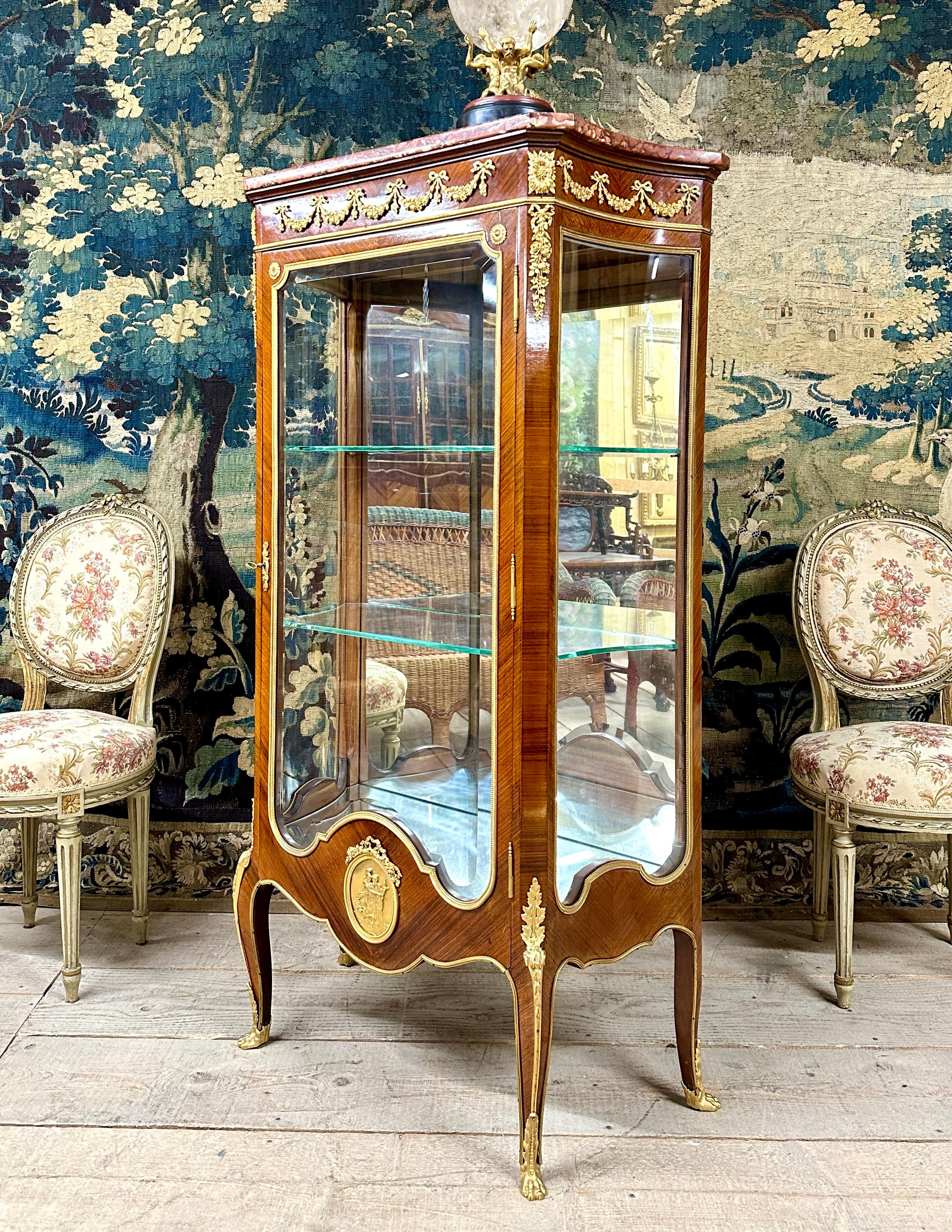 Beautiful Louis XVI style showcase richly decorated with gilded bronzes screwed to the furniture with in particular a medallion in low relief in the lower part. Work of good quality in violet wood. The curved side parts and the bevelled front glass.