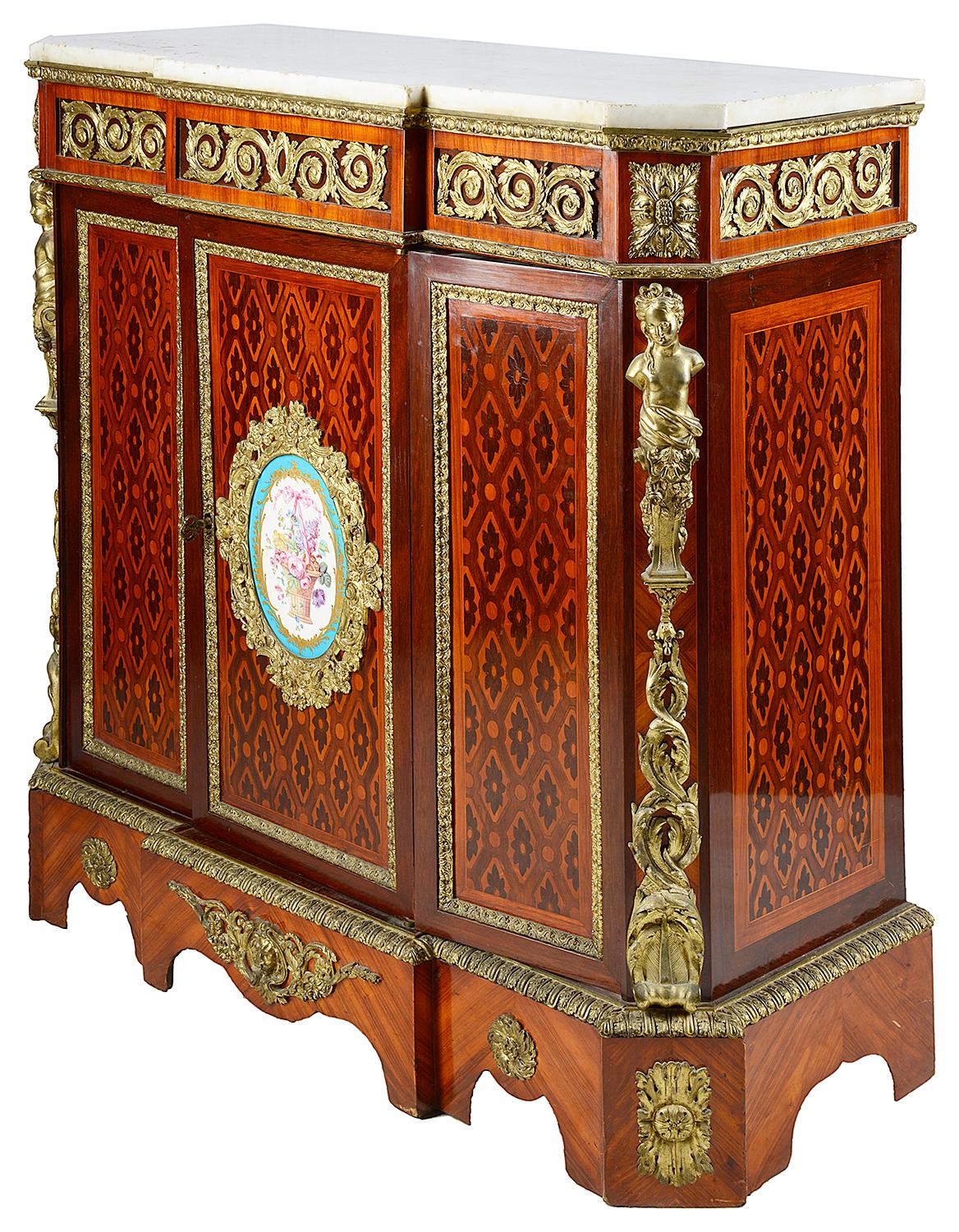 A good quality late 19th century side cabinet, having a white marble top, gilded ormolu scrolling mounts to the frieze, various exotic woods to the parquetry and marquetry inlay, a Sevres style porcelain plaque with flowers in a basket to the