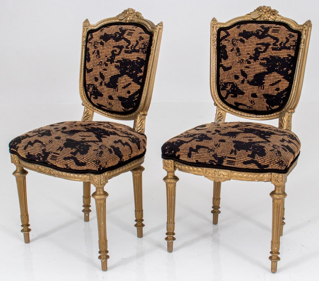 Louis XVI Style gold-painted side chairs, each with shaped crestail centering musical trophies, the seat and back upholstered in black and taupe fluted legs with toupie feet.

Dealer: S138XX