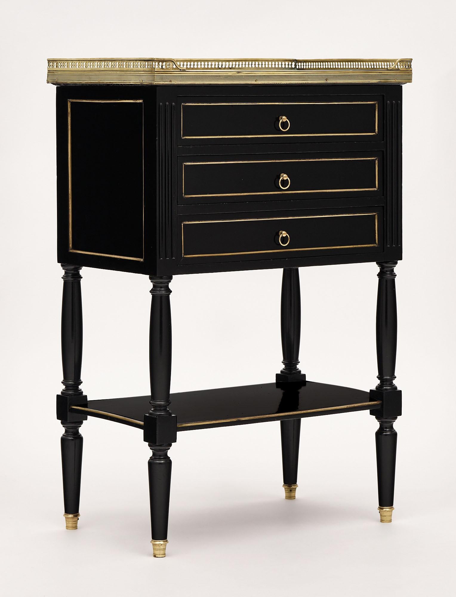 Side table from France in the Louis XVI style made of mahogany and ebonized with a lustrous museum quality French polish. There are three dovetailed drawers above a lower shelf supported by toupees legs. The top is a Carrara marble surrounded by a