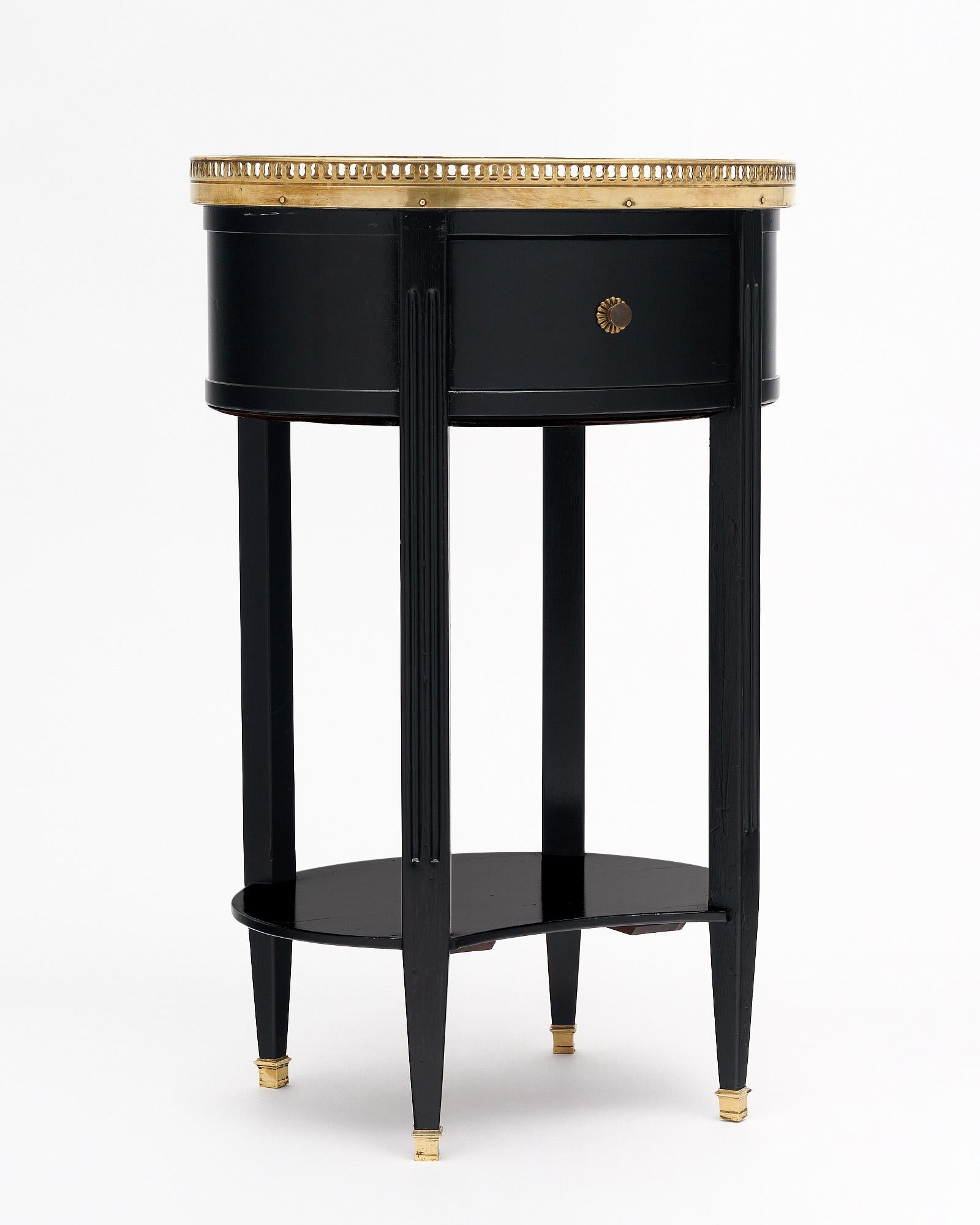 Side table from France in the Louis XVI style. This piece has been ebonized and finished with a lustrous French polish of museum-quality. There is one dovetailed drawer and a lower shelf for functionality. The Carrara marble top is encircled with a
