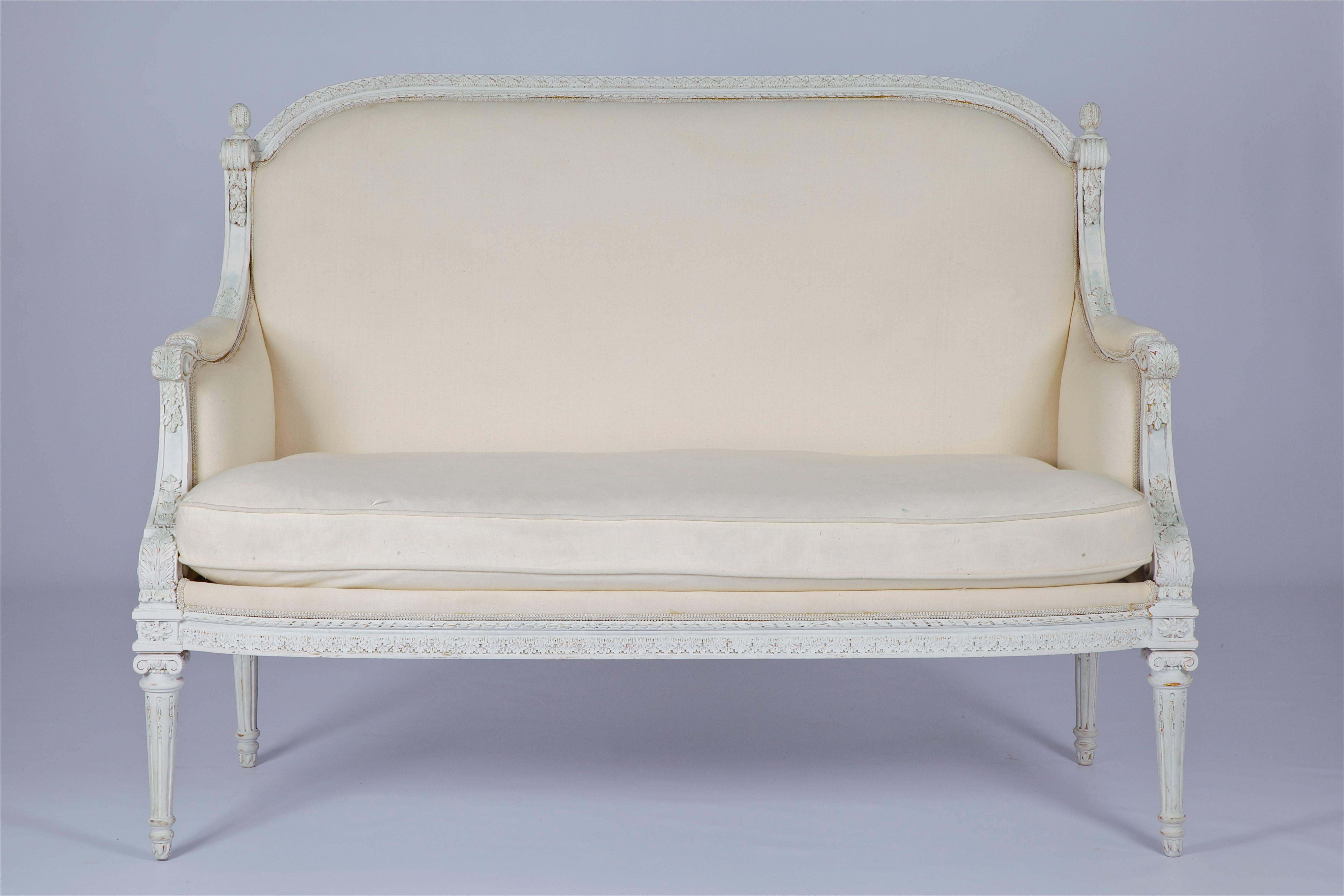 French Louis XVI style two-seat sofa, hand-carved in solid wood, upholstered with a white Calico and painted in an aged white gesso.