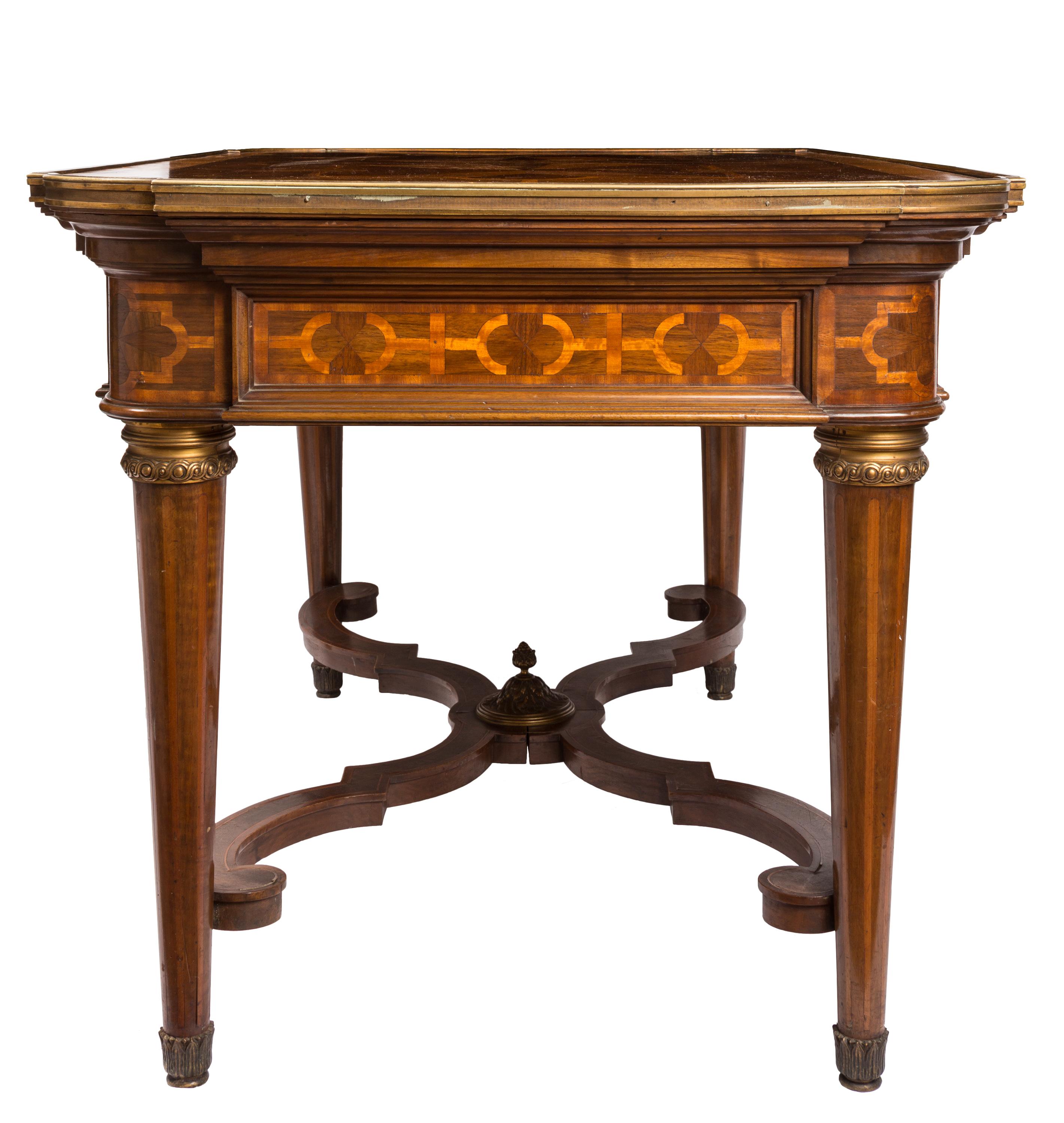 A 19th century French center table in Louis XVI style, featuring unusual geometric marquetry of various types of wood veneer on top, sides and legs. The tabletop is edged with a brass molding, and each tapered leg features a decorative brass collar