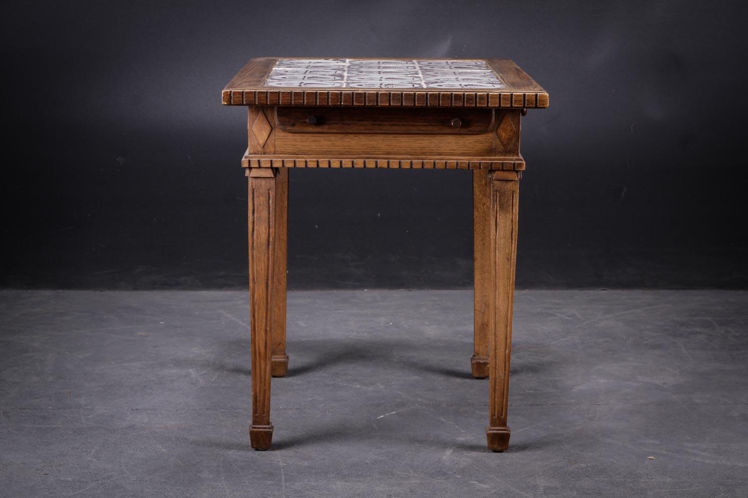 Louis XVI style table, Danish, in oak with dentil molding, inlaid with 15 faience tiles decorated in manganese with flower vases. 19th century.
