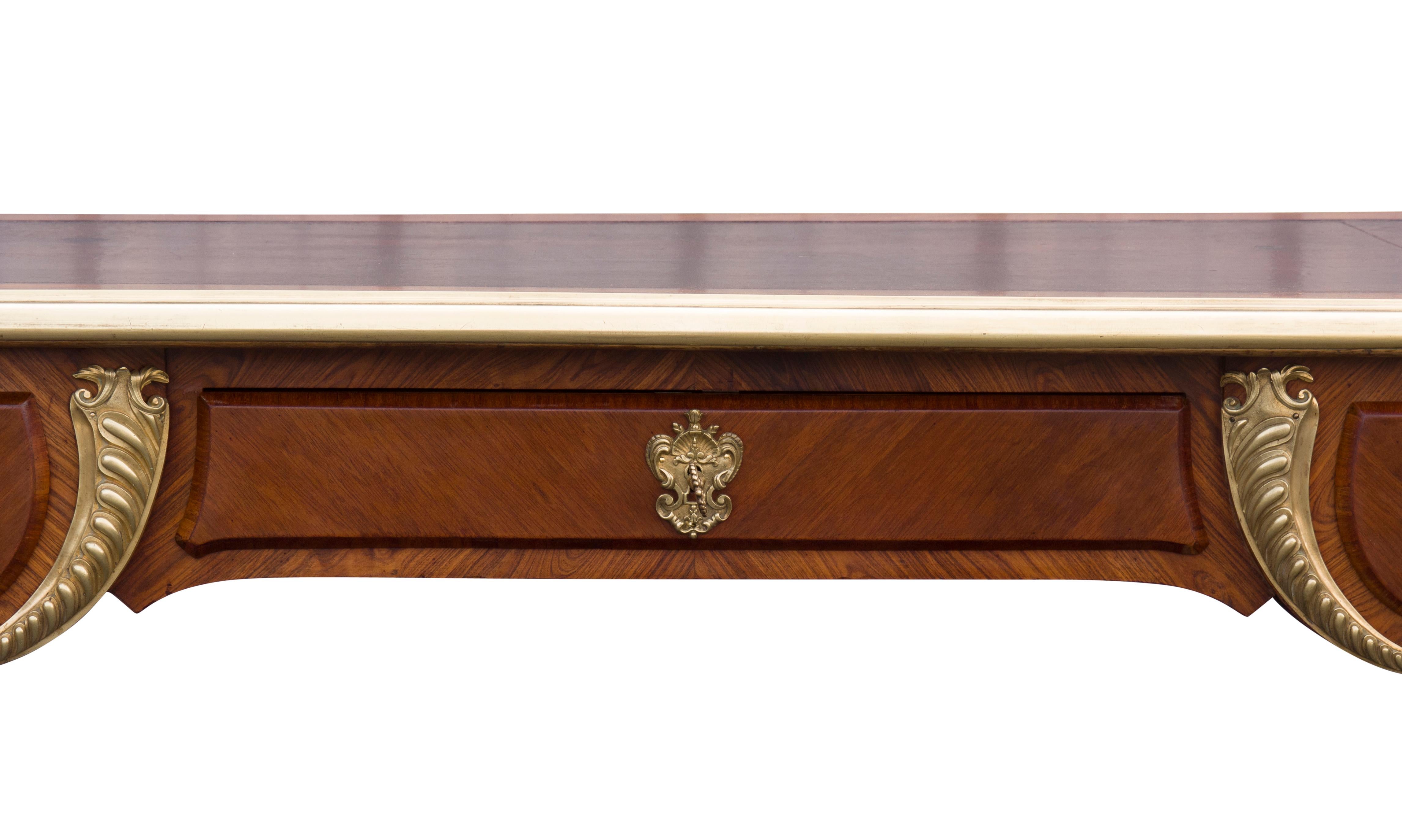 With a rectangular top with inset deep burgundy leather with bronze outer border over three drawers and opposing false drawers raised on cabriole legs and sabot feet. With key.