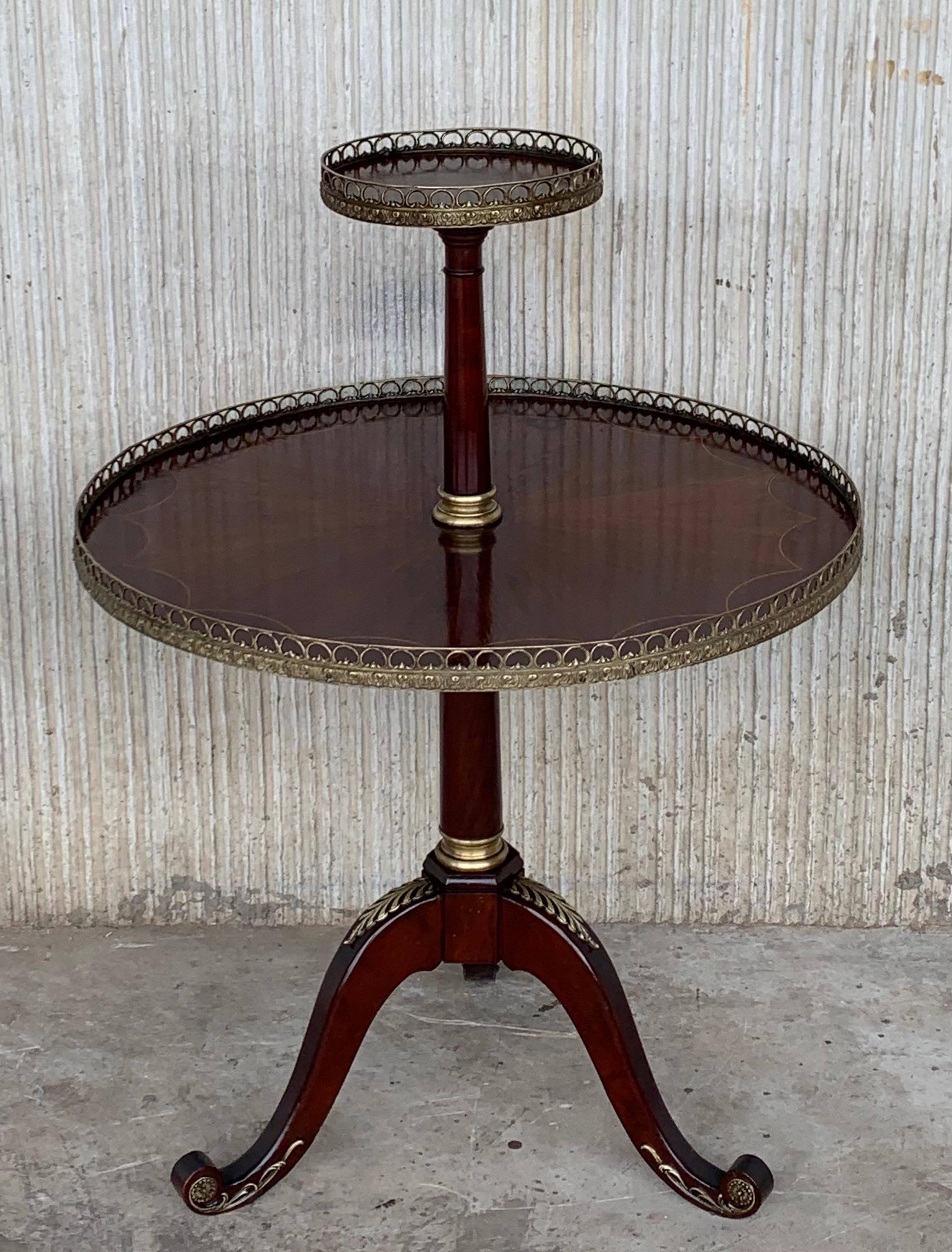 Mesa auxiliar de dos niveles de estilo Luis XVI, procedente de Francia, con marquetería de sol en el estante inferior. Ambas presentan galerías de latón y la pieza se apoya en cuatro patas cónicas con pies de bronce.

Medida: Altura hasta la
