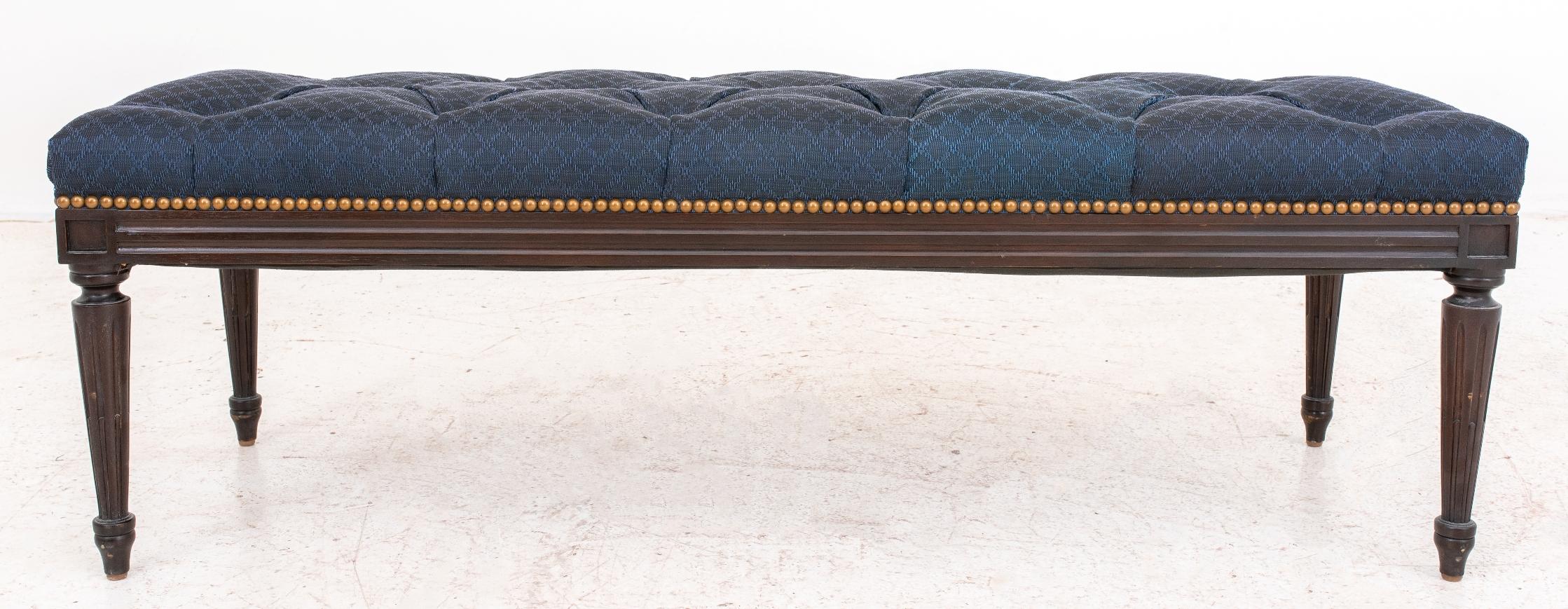 French Louis XVI style ebonized mahogany ottoman on bench, raised on fluted tapered legs, upholstered in blue jacquard fabric. Some fading visible on fabric. In good vintage condition. Wear consistent with age and use.

Dimensions: 15.5