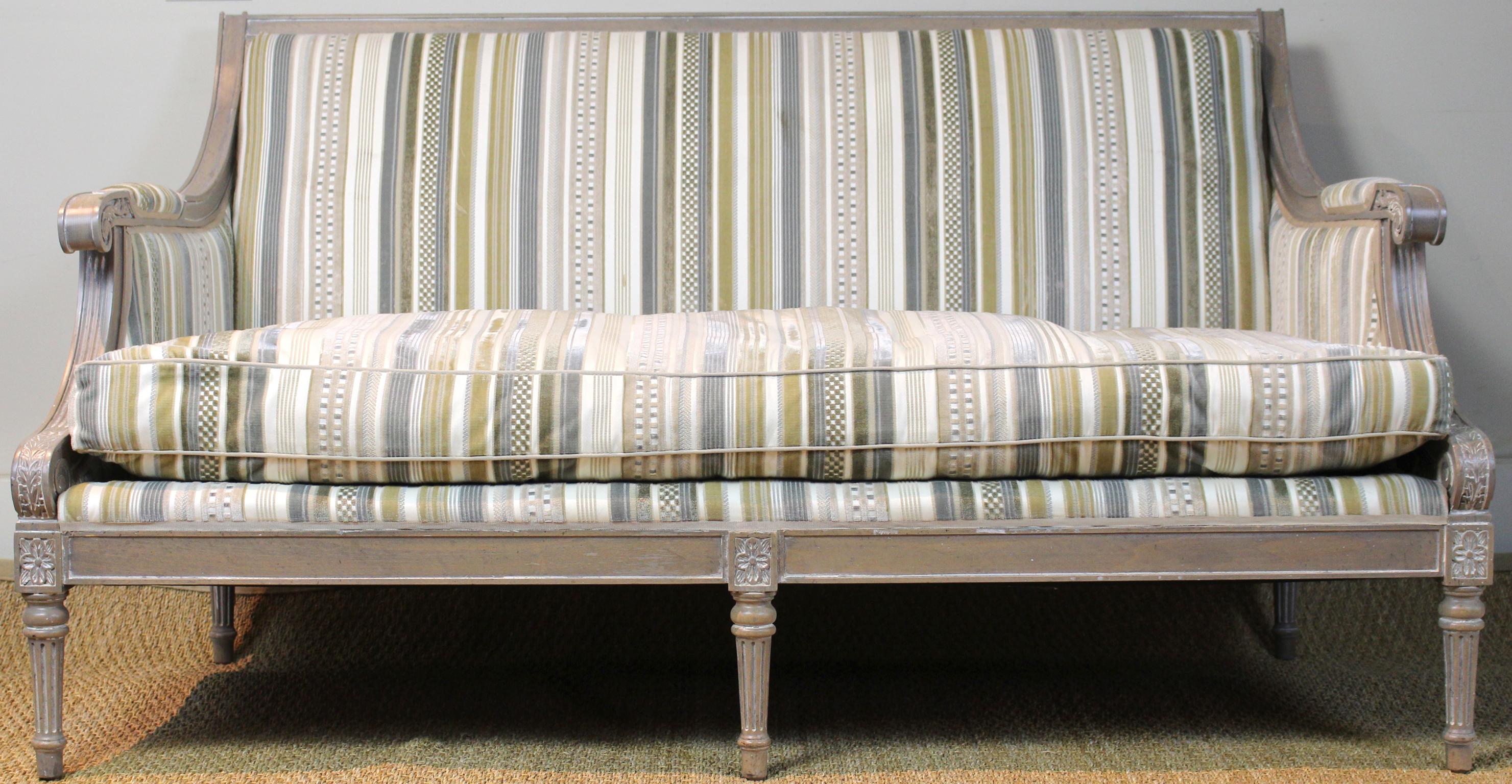 An elegant late 20th century Louis XVI style carved and painted small sofa with loose down-filled cushion newly upholstered in a nuetral striped silk velvet fabric.