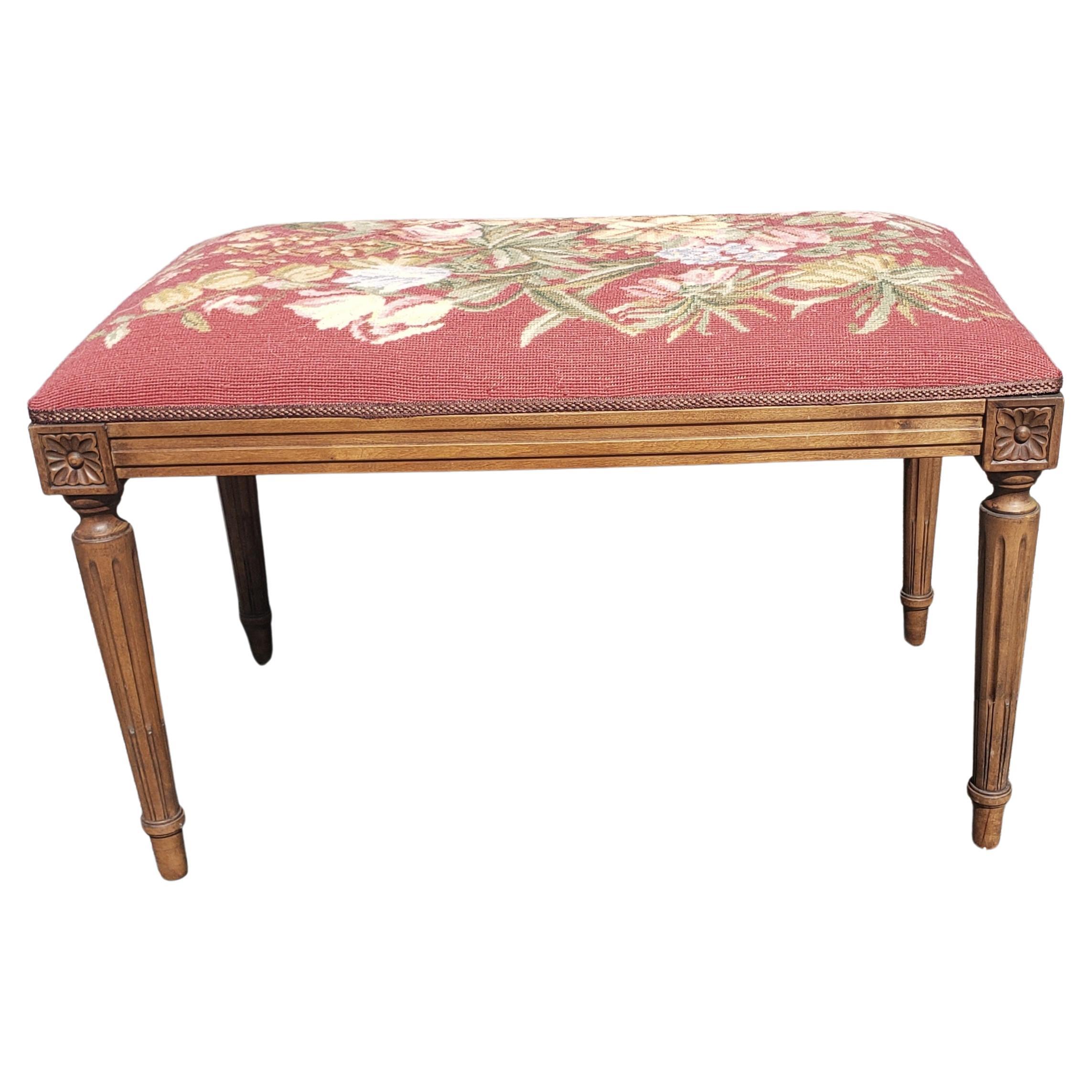 A Louis XVI style walnut tabouret bench late 20th century, having a needlework top, above ribbon carved and fluted walnut legs. Wonderful warm patina to the surface. Measures 31.5