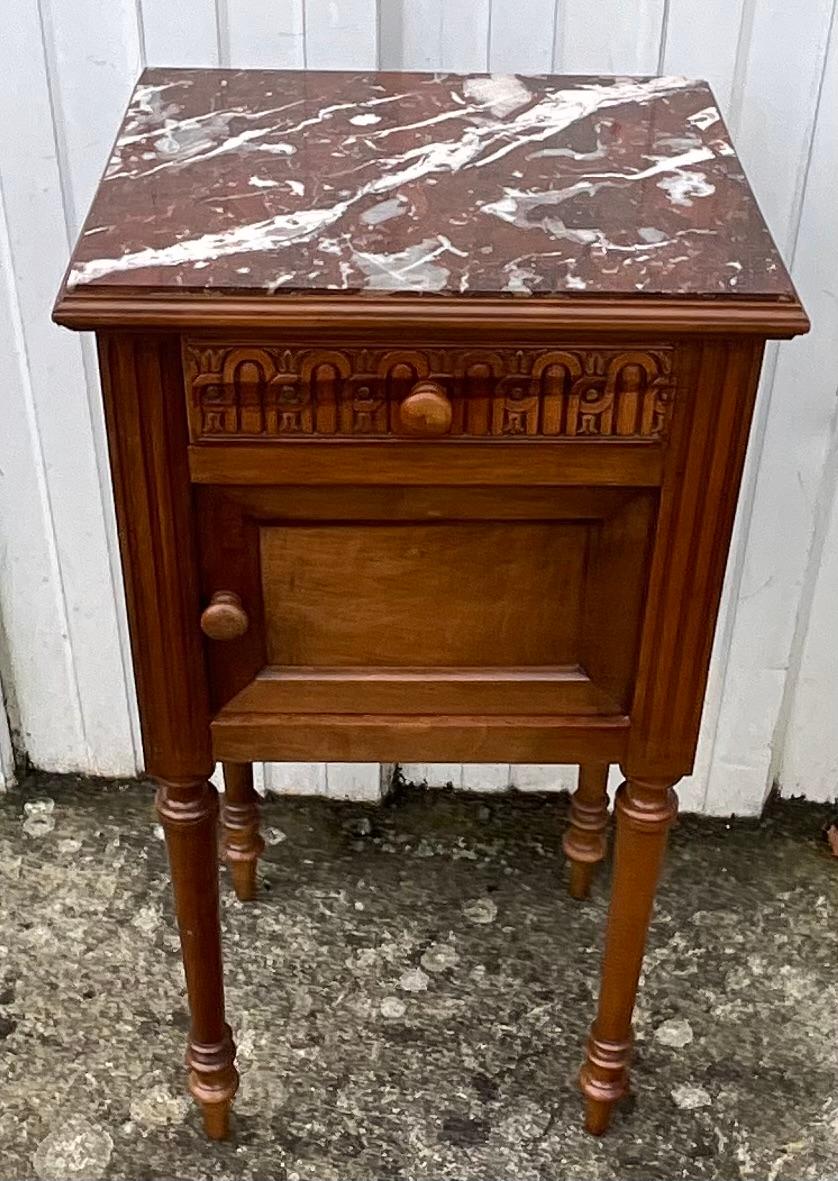 Elegante comodino in noce dei primi del Novecento, progettato in stile Luigi XVI. Questo raffinato pezzo poggia su quattro gambe tornite, tipiche dell'epoca, e presenta una bella patina calda che mette in risalto la qualità del legno di noce. Il suo