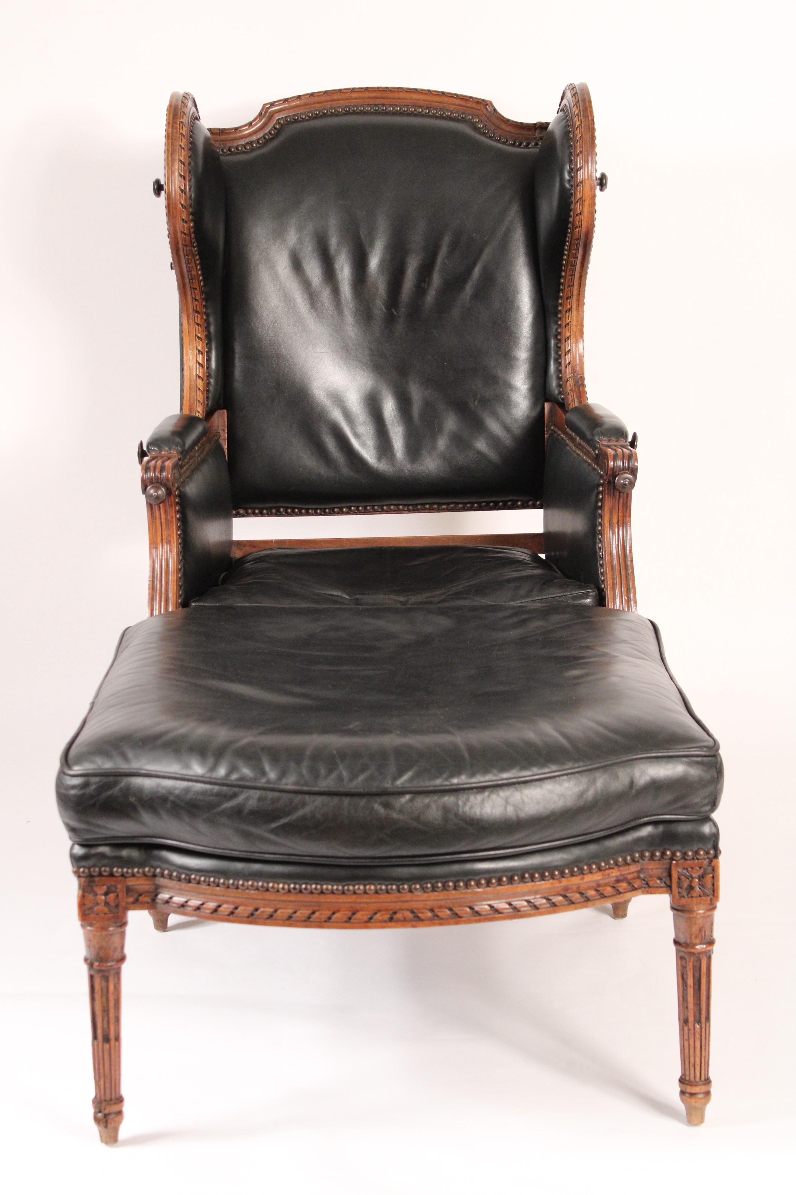 Antique Louis XVI style carved walnut ducheese brisee with leather upholstery, 19th century. 
The winged bergere with an adjustable back and iron tray supports that come out of the front of the arms. Dimensions of the bergere, height 46
