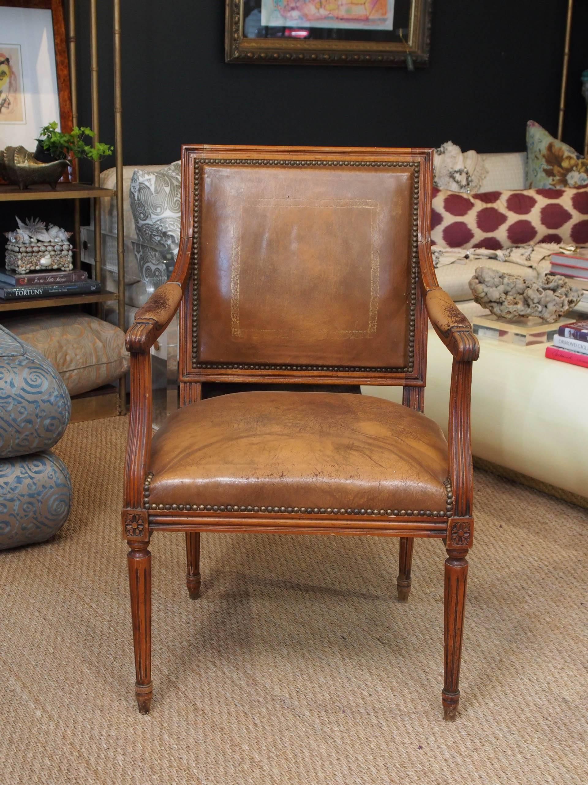 Louis XVI style walnut fauteuil chair with original leather and nailhead trim.