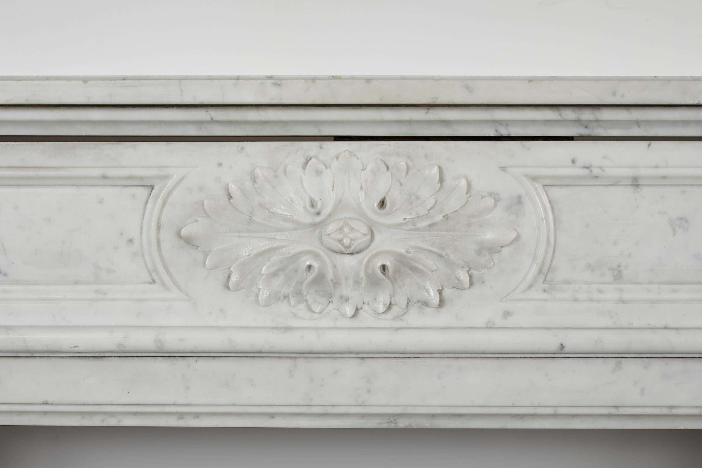 Louis XVI style white Carrara marble mantel with semi columns and floral motifs.
Interior dimensions H 33.5 x W 43.25.
 