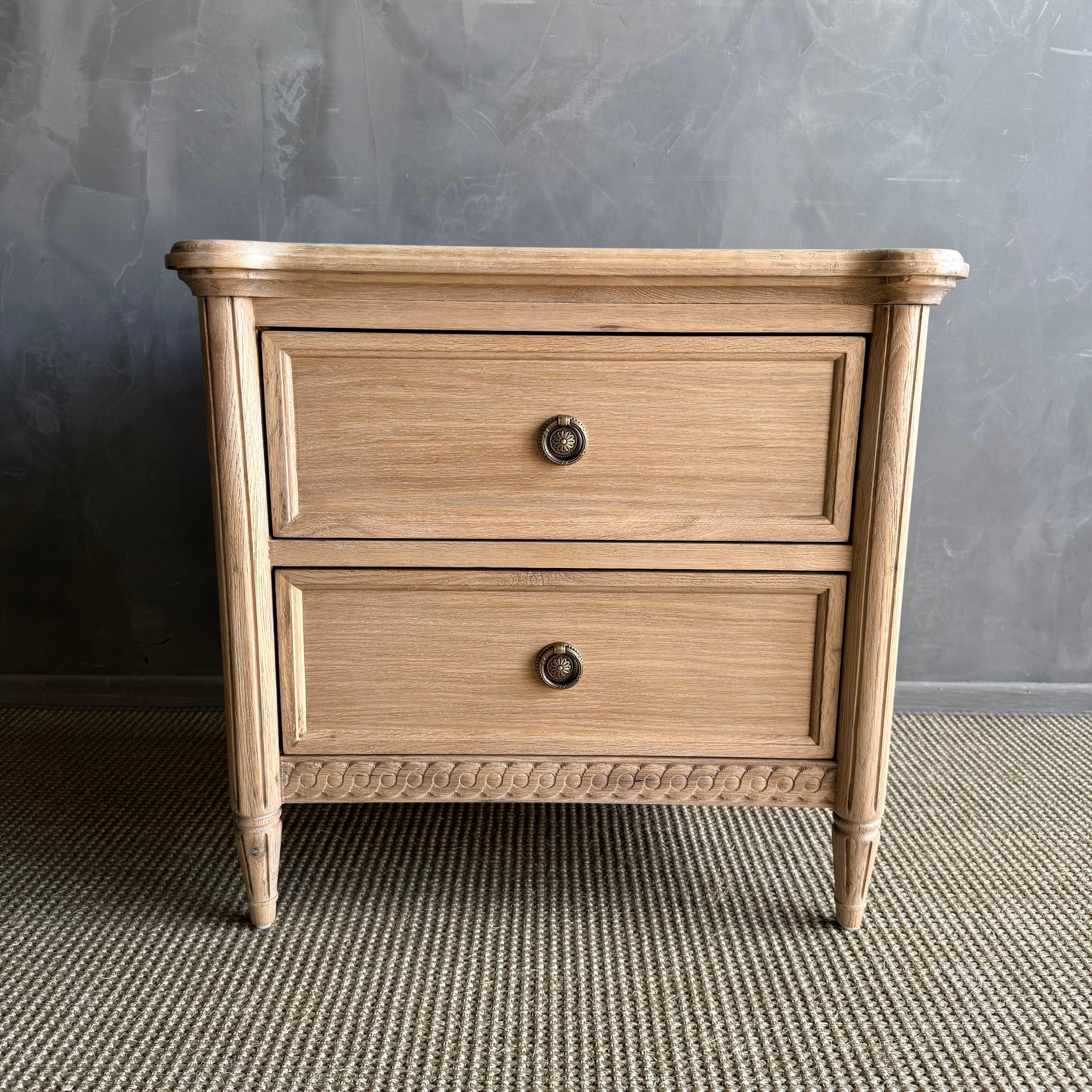 Eleg votre chambre à coucher avec cette table de nuit à deux tiroirs d'inspiration Louis XVI intemporelle, fabriquée avec soin pour concilier l'élégance classique et la fonctionnalité au quotidien. Construit en chêne blanc massif et en placages de