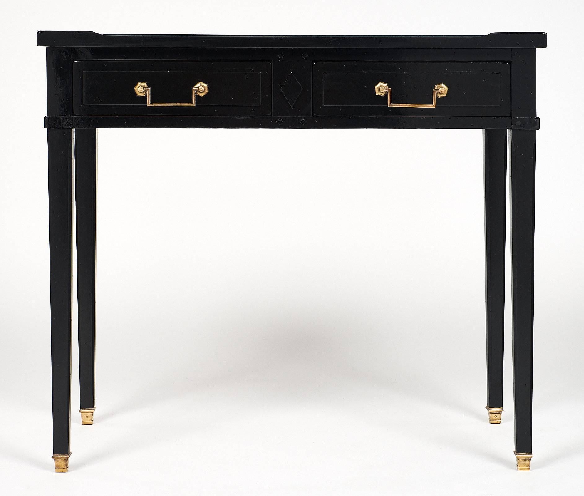 Charming French Louis XVI style writing desk made of ebonized mahogany, and featuring a mirrored top. This desk has two dovetailed drawers with gilt bronze handles and bronze on all four feet. We love the elegance of the tapered legs and paneled