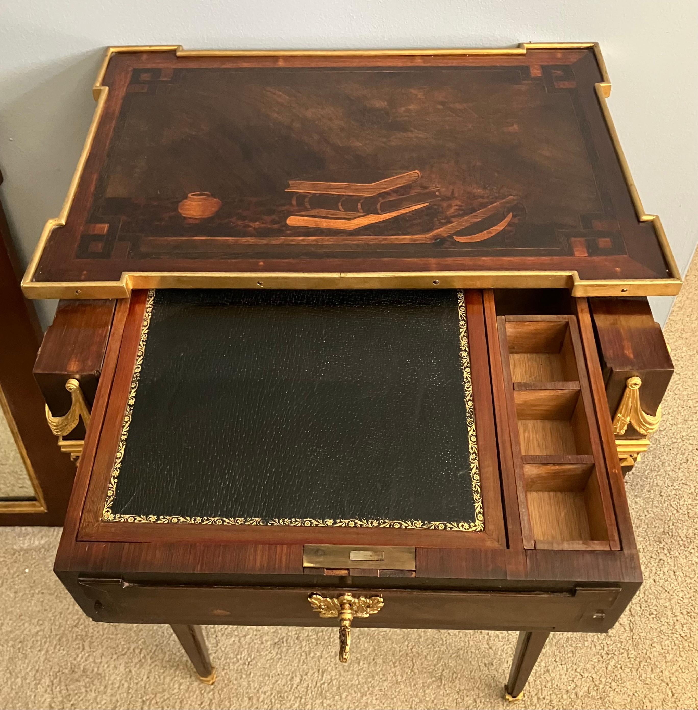 Louis XVI style side table writing table / nightstand with ormolu mounts. 
Unusual small writing table in fine Louis XVI style in mahogany featuring a block bronze lined top featuring marquetery design of books and an inkwell on a faux tortoise