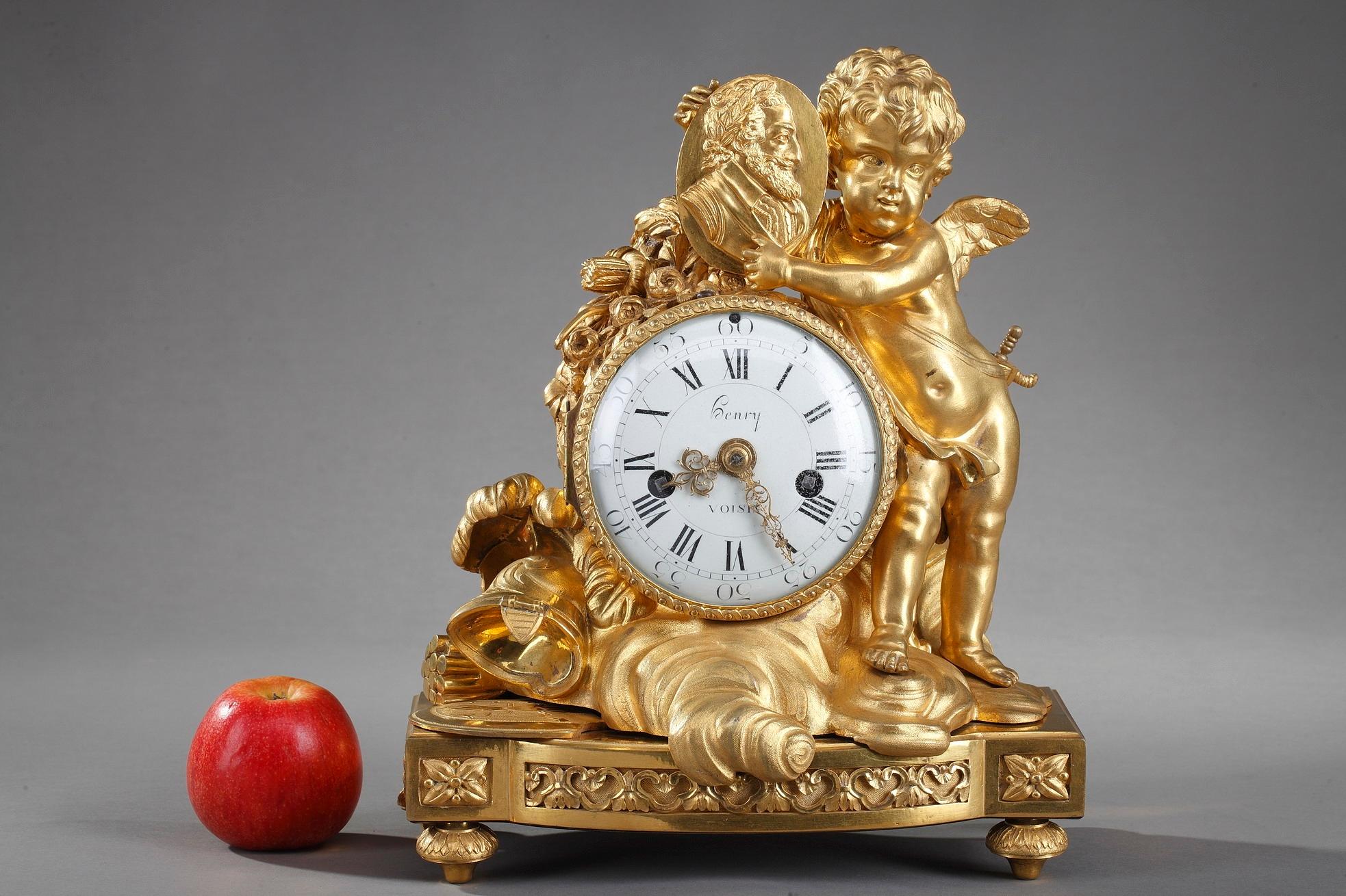 Late 18th century Louis XVI table clock crafted in gilt bronze featuring a winged Cupid presenting a medallion portrait of the founder of the Bourbon dynasty in France, the king Henri IV (1553-1610). Cupid carries the sword, symbol of the king's