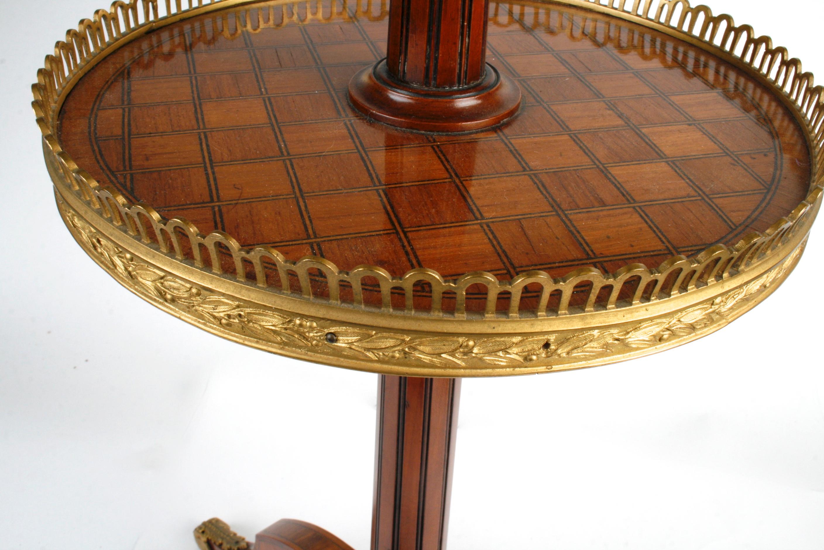 This exceptional two tiered table has intricately, parquetry inlaid tops banded with gilt pierced galleries. It stands on a reeded central column and inlaid tripod feet with gilt Acanthus shoes. An elegant small table for a beautifully detailed