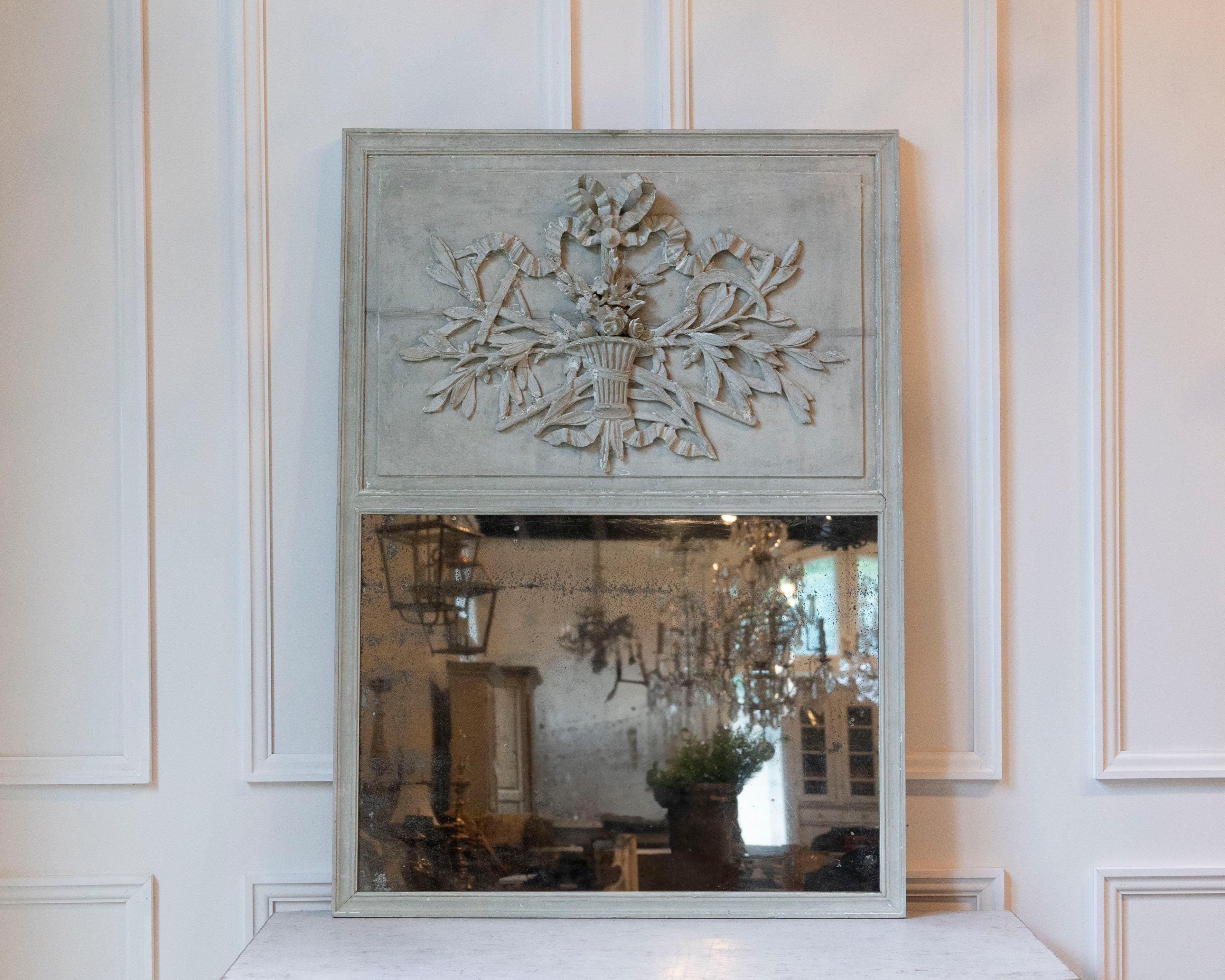 Un superbo trumeau di epoca Luigi XVI, tra la fine del XVIII e l'inizio del XIX secolo, in legno intagliato e con la finitura originale dipinta. Il pannello superiore è finemente decorato con un cesto di fiori fiancheggiato da un fogliame che