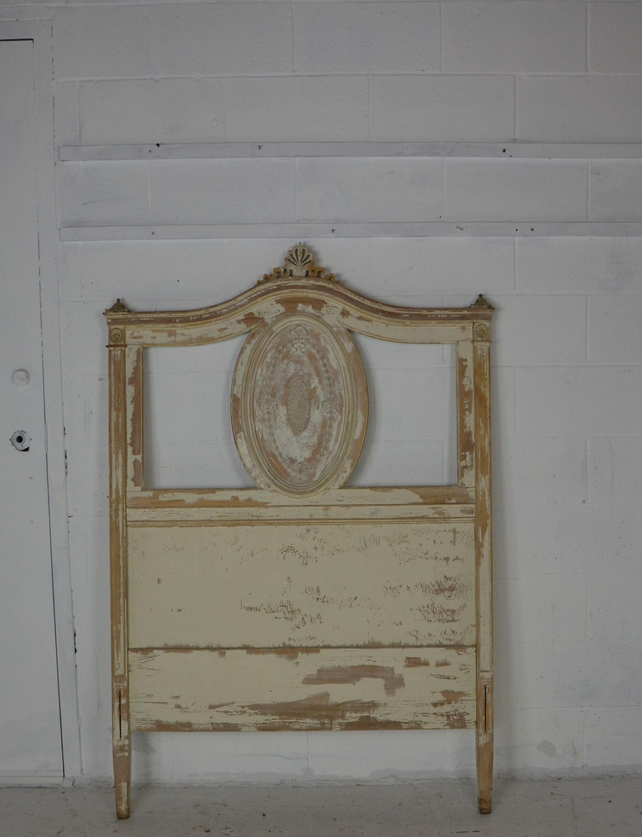 A Louis XVI twin bed frame in a shabby paint finish. The center panel with a raised medallion surrounded by a wreath of bluebells and ribbons.