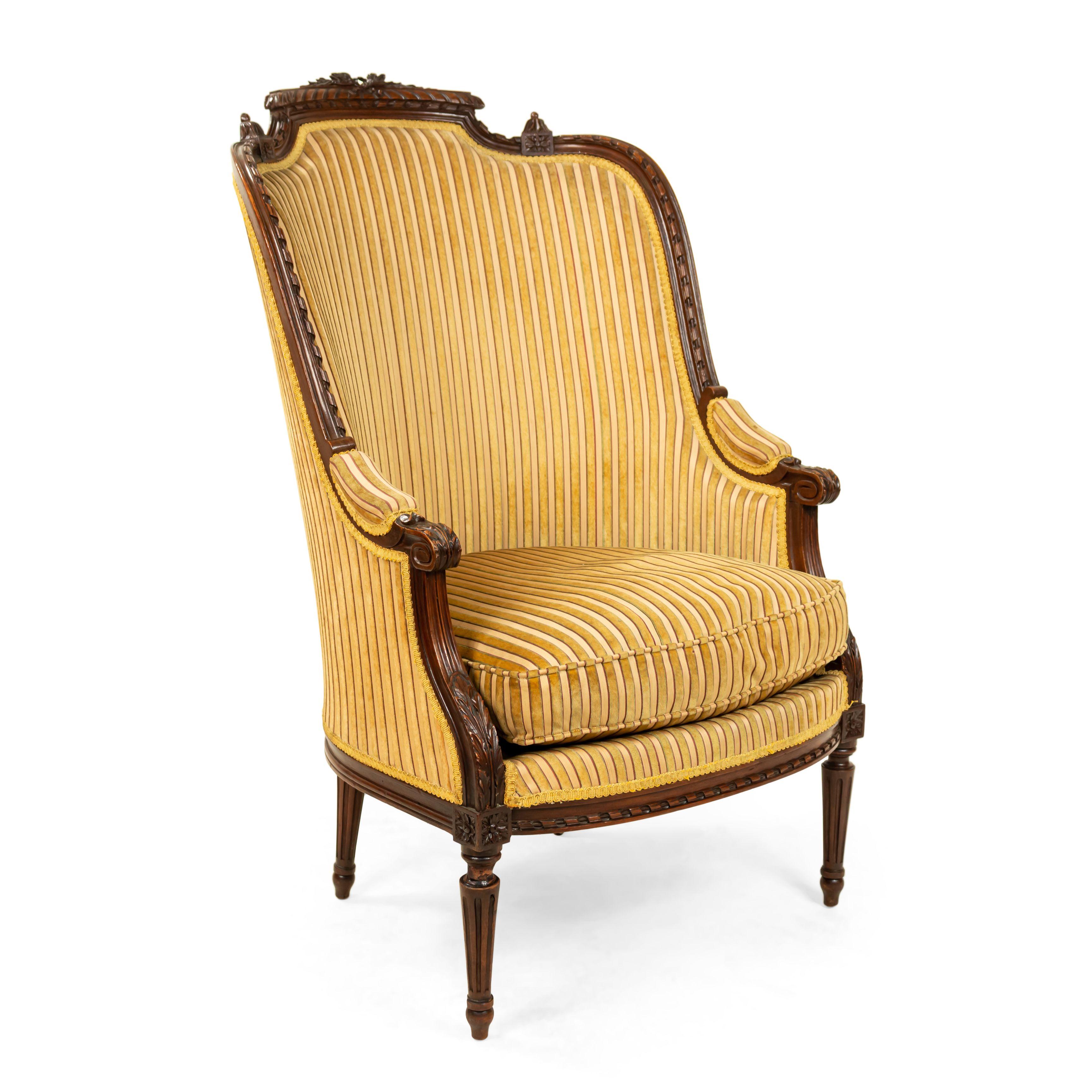 Pair of French Louis XVI style (19th century) walnut bergère armchairs with bow knot top and striped upholstery.