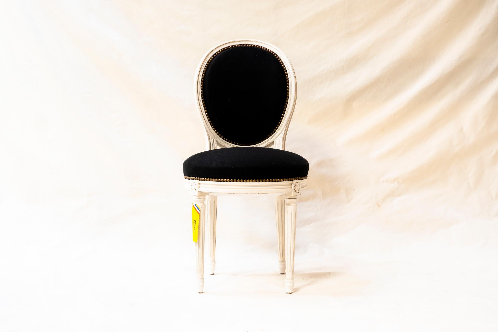 Six whitewashed round back and round seat Louis XVI chairs, recovered in the last century in black velvet. Perfect for a dining room or kitchen, they may be recovered in a fabric of choice or kept as is for many years.