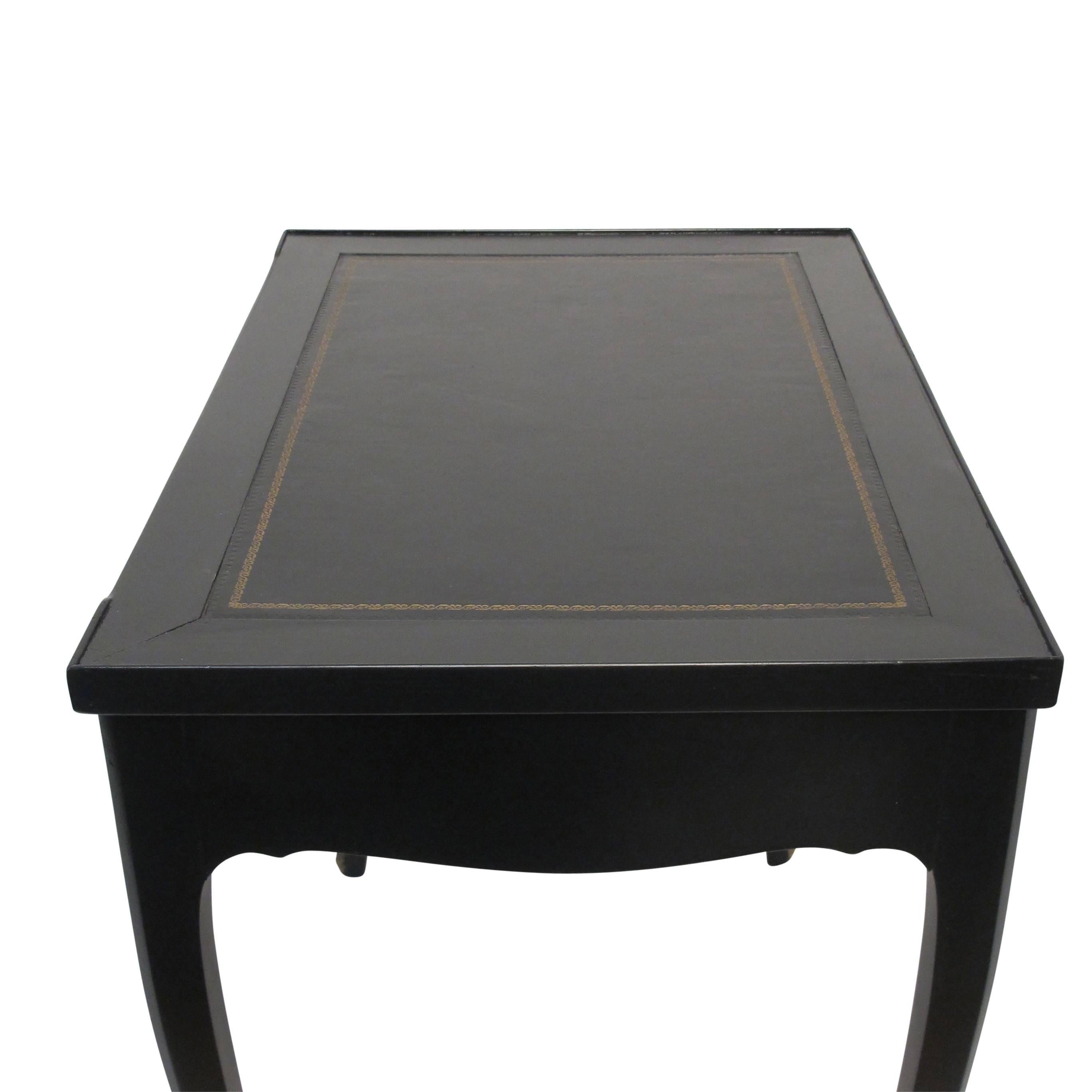 Stylish black lacquered writing table and tric trac games table. The writing surface having inset leather with gold tooling. The interior of the games table inlaid with green and yellow backgammon board, the reverse of the top laid with green baize