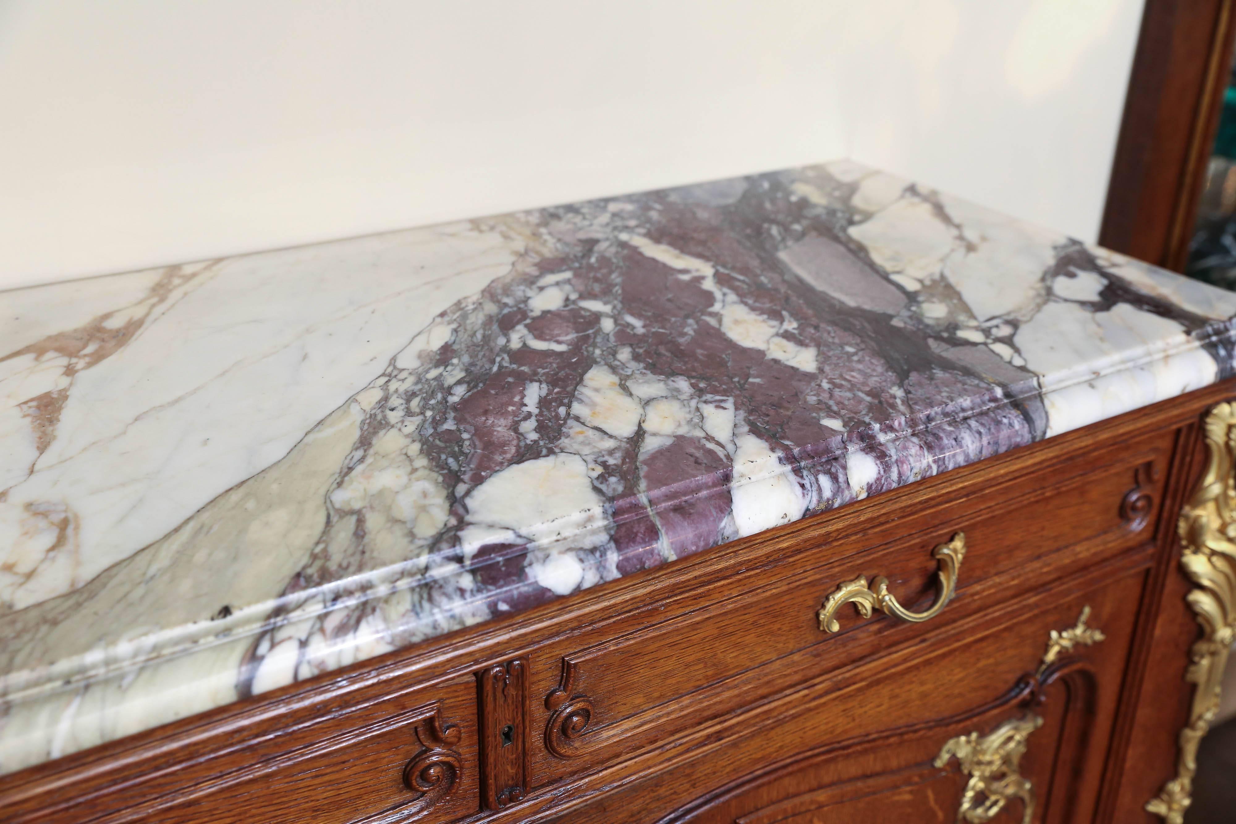 Early 20th century, marble-top with projecting rounded corners, above
a conforming case fitted with two drawers over two cupboard doors,
all inset with shaped panels, raised on splayed legs and sabots, the
back bearing the stamp “Haentges Fres.