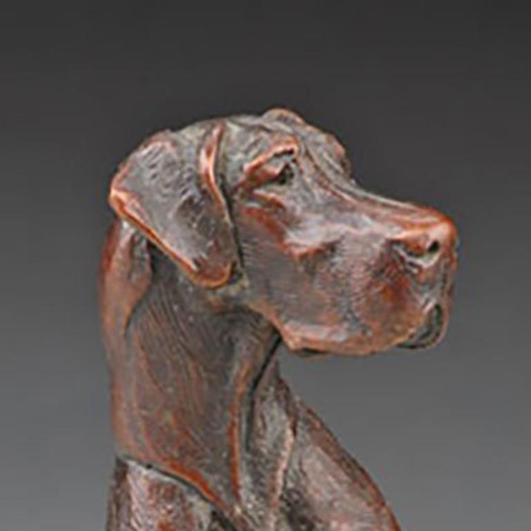 Sculpture of a dog sitting up and looking to the side. 
Ed. 58/99