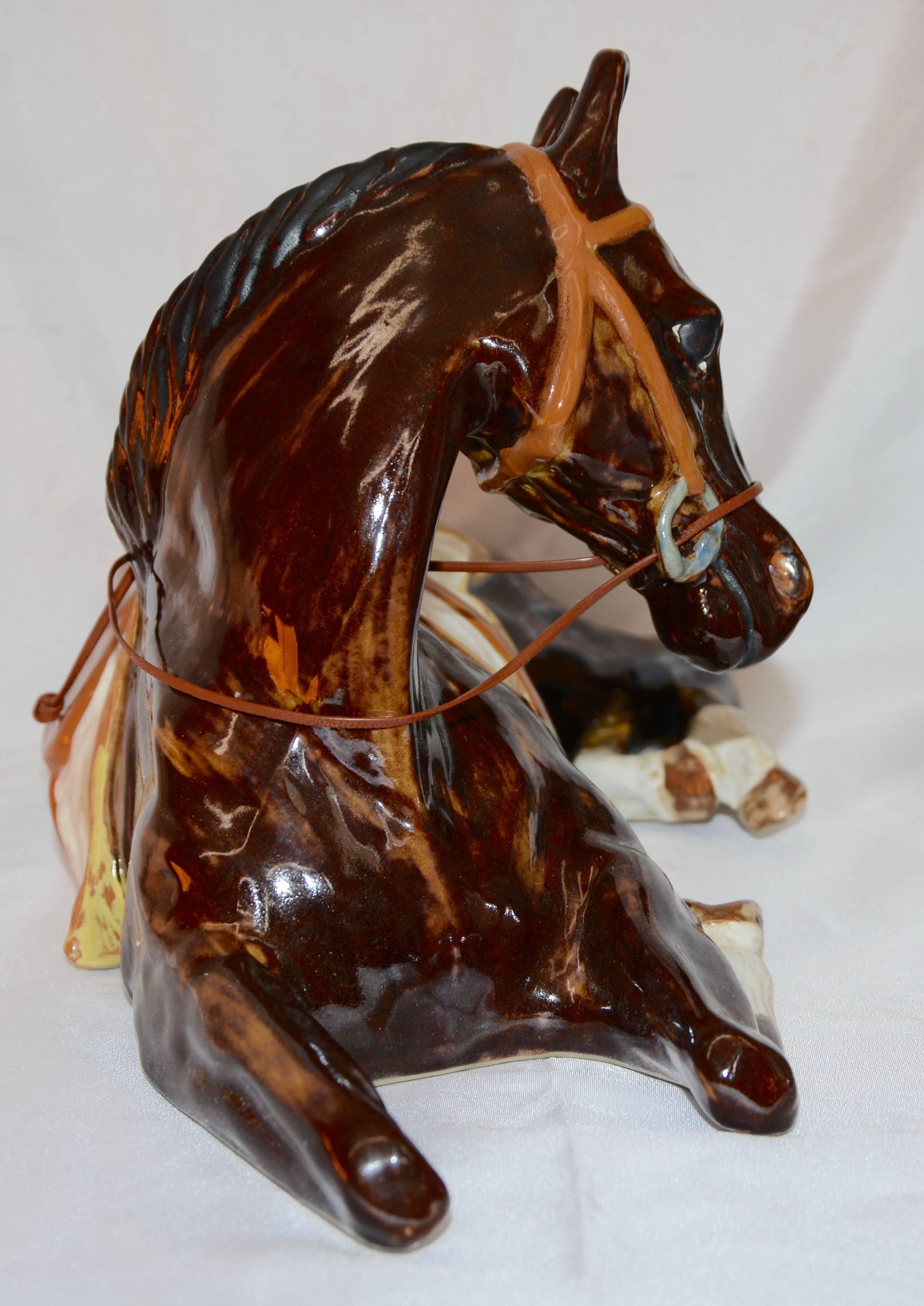 This is a tranquil horse at rest made by the Louisville Stoneware Co. of Kentucky. He is made of ceramic and has been artfully glazed in appropriate colors. He comes with reins made of a vinyl cord.