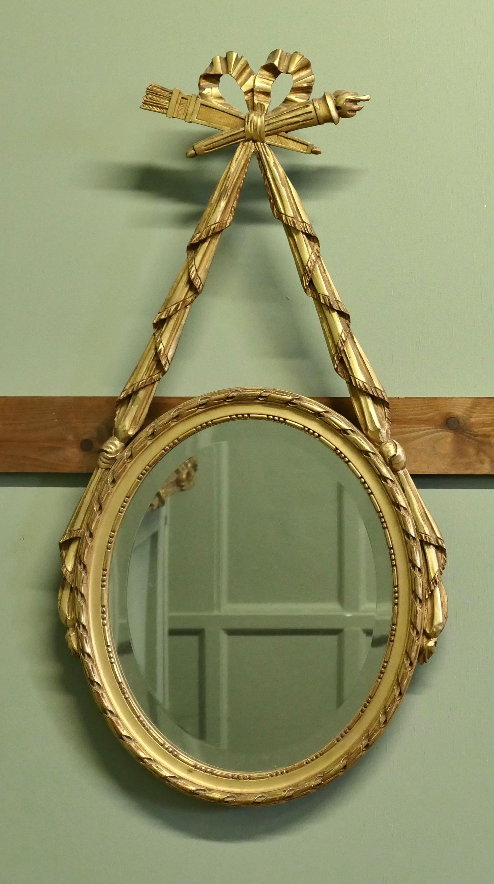 LouisXVI Style Gilt Ribbon and Bow Mirror Oval Mirror

A superb piece hand carved with swags and a large bow at the top giving the  impression that the beveled mirror is hanging from a golden ribbon 
A lovely piece in good condition, the overall