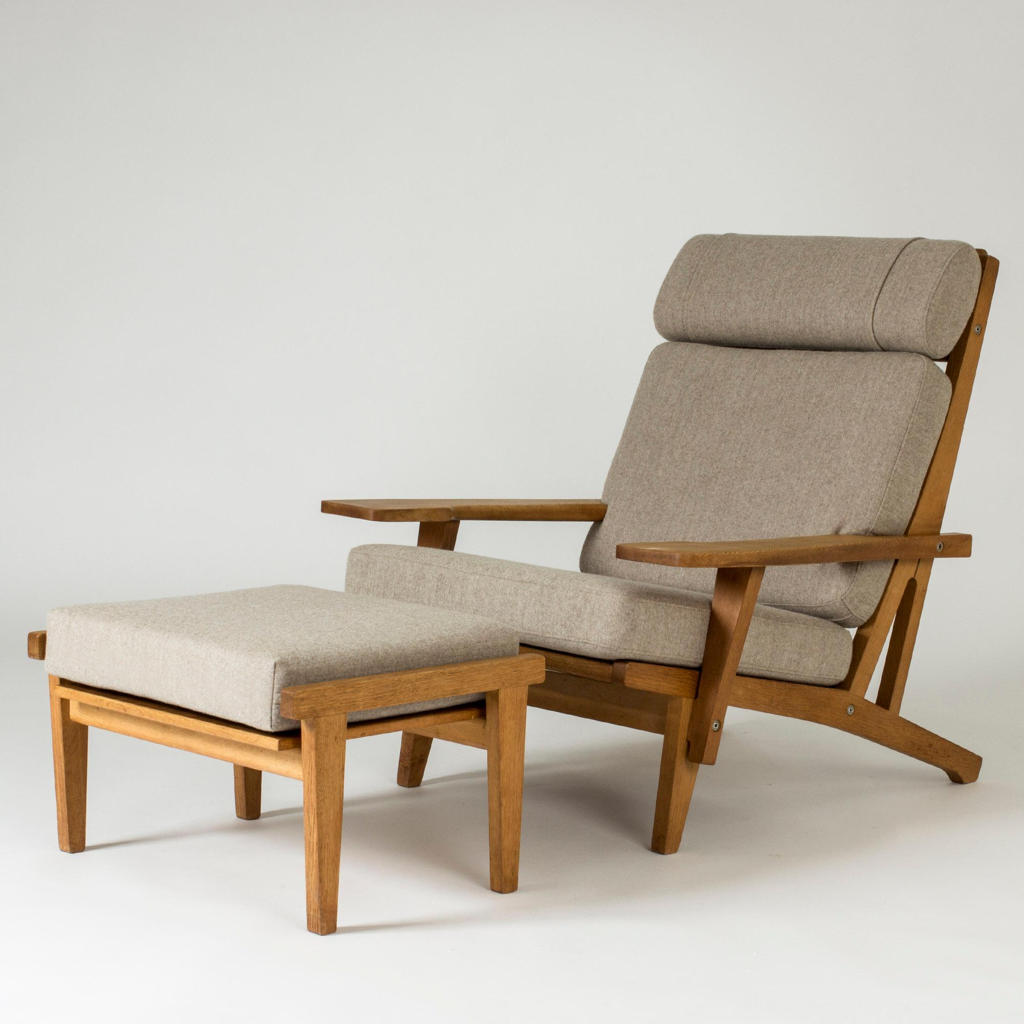 Cool lounge chair and footstool by Hans J. Wegner, with wide proportions. Elegant, sturdy lines. Made from oak with wool upholstery in a warm oatmeal tone.
