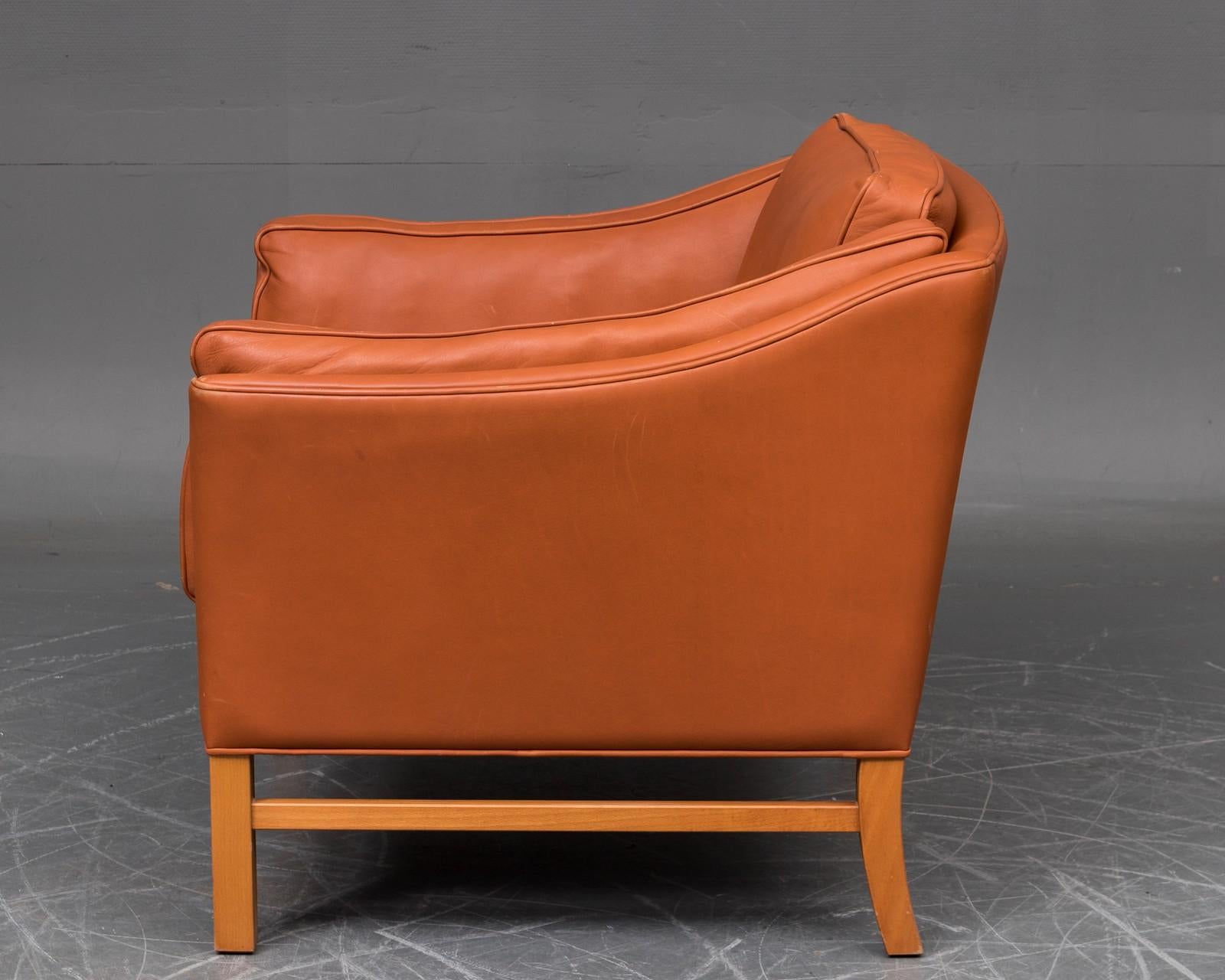 Very comfortable armchair by Grant Møbelfabrik, Denmark. Lounge chair covered with cognac-colored leather. Beech wood frame. Measures: H 78 cm, SH 46 cm. Traces of wear, some marks on leather.