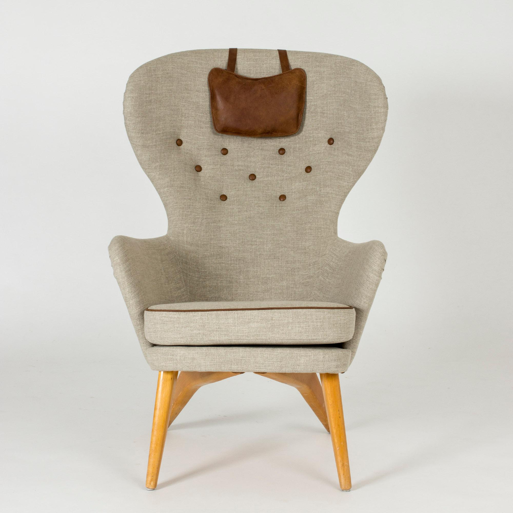 Cool lounge chair by Gustaf Hiort af Ornäs, with a tall, wide back and amazing silhouette. Brown leather piping, buttons and small neck cushion.