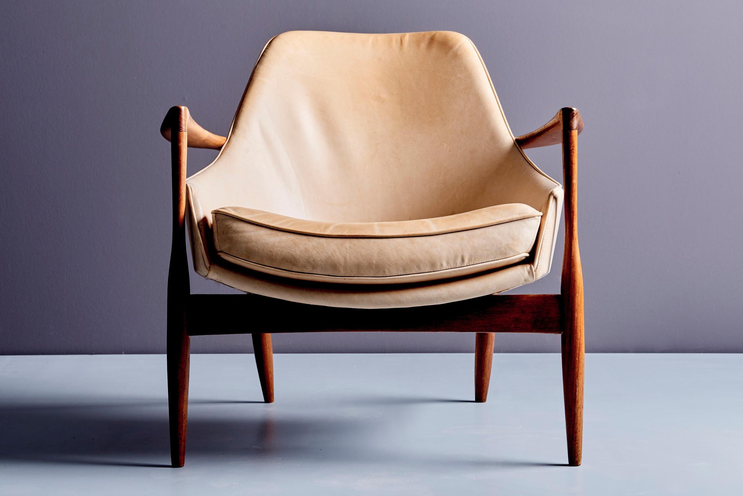 Una rara poltrona danese disegnata da Ib Kofod-Larsen per G. Laauser nel 1955. Questo pezzo elegante presenta una struttura in legno di teak splendidamente scolpita con uno schienale delicatamente vaporizzato, che mette in mostra la raffinata