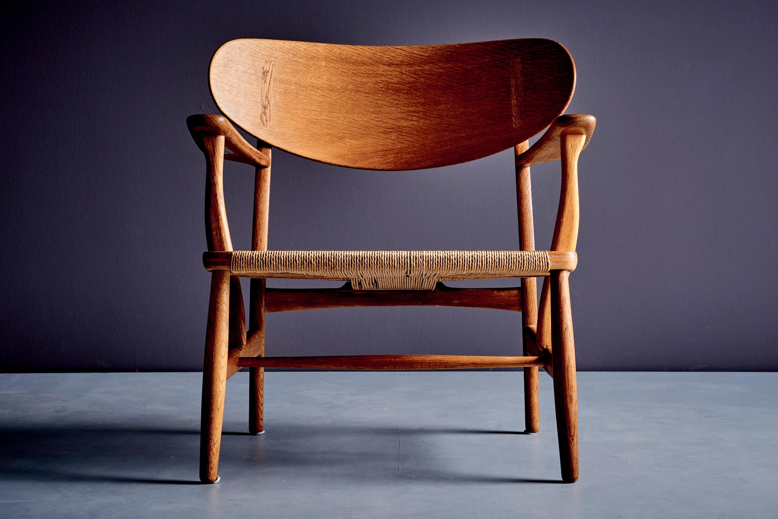 La chaise longue Hans Wegner CH22 est une création du designer danois Hans J. Wegner pour Carl Hansen & Søn. Il s'agit d'un fauteuil bas construit en bois massif, doté d'accoudoirs aux formes caractéristiques et d'une assise en corde de papier au