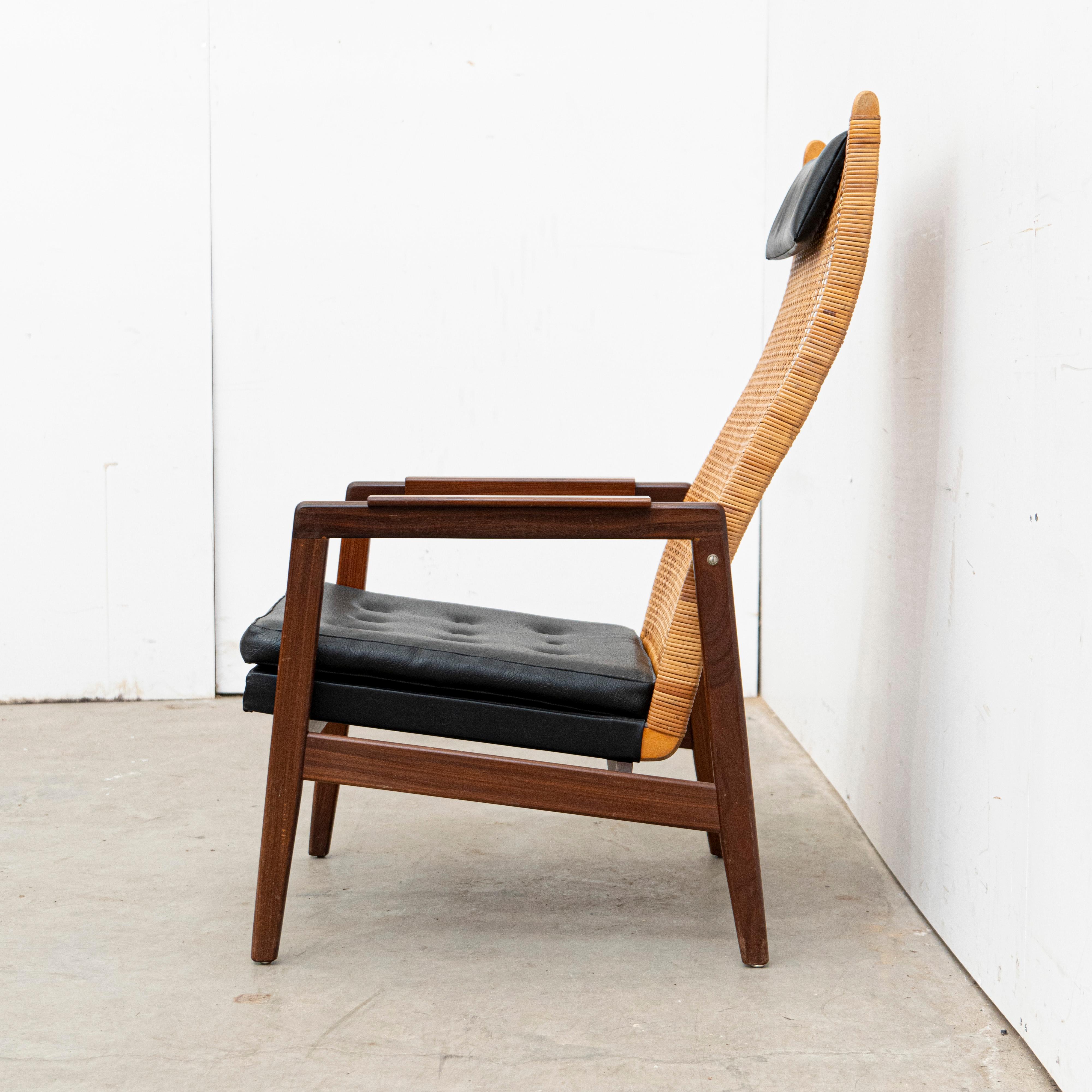Lounge chair designed by Muntendam for Gebroeders Jonkers in the 1960s, showcasing a stylish and functional design. The chair features a sleek wooden frame, a woven rattan backrest, and comfortable faux leather upholstery, combining mid-century