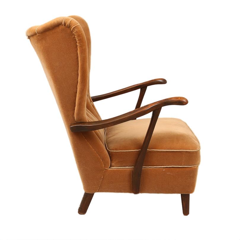 Discover the timeless elegance of this sophisticated wing chair from the 20th century, a charming jewel that fuses dark wood with an original light brown velvet fabric. This decoration classic is a unique piece that evokes the distinction and