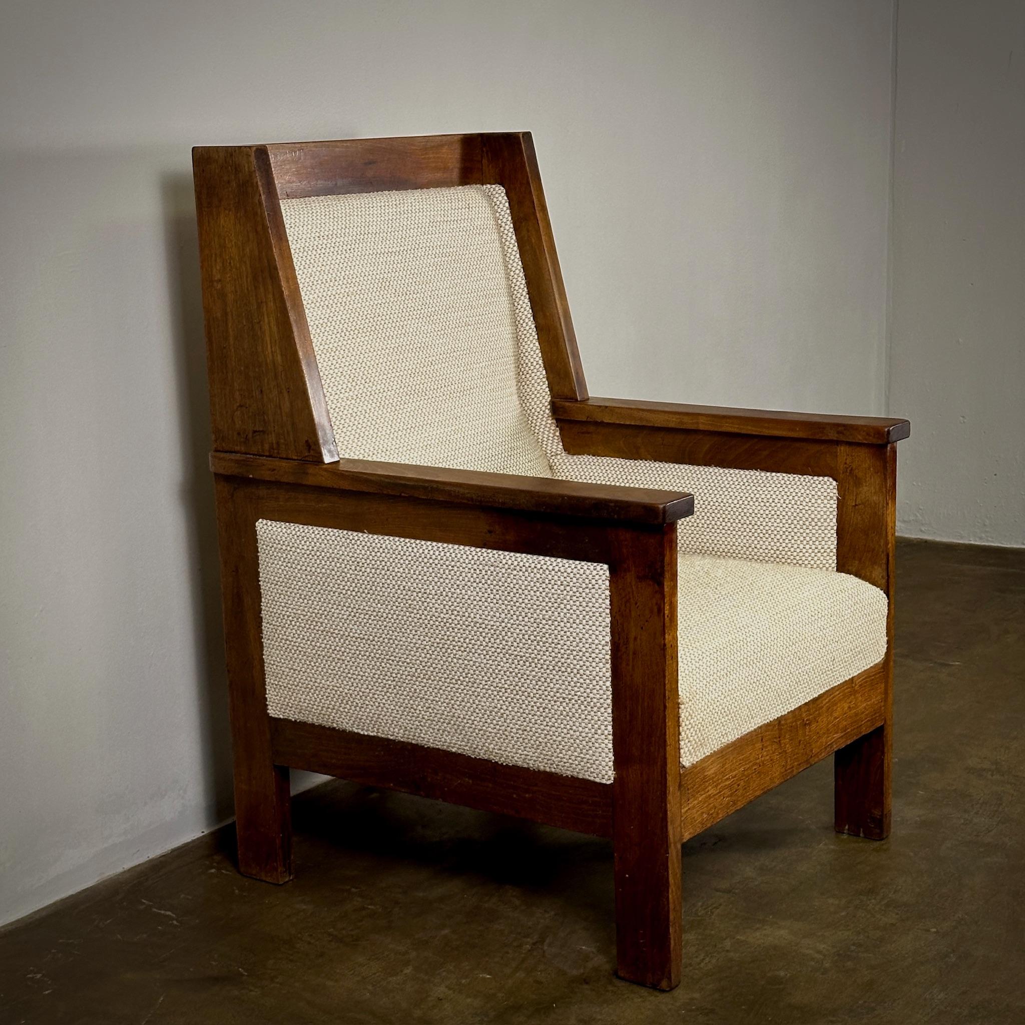 This 1930s Dutch lounge chair, designed by the legendary Hendrik Wouda in the Amsterdam School style, captures a unique blend of functionality and artistic flair. The chair's carved oak frame supports a beautifully textured ivory upholstery,